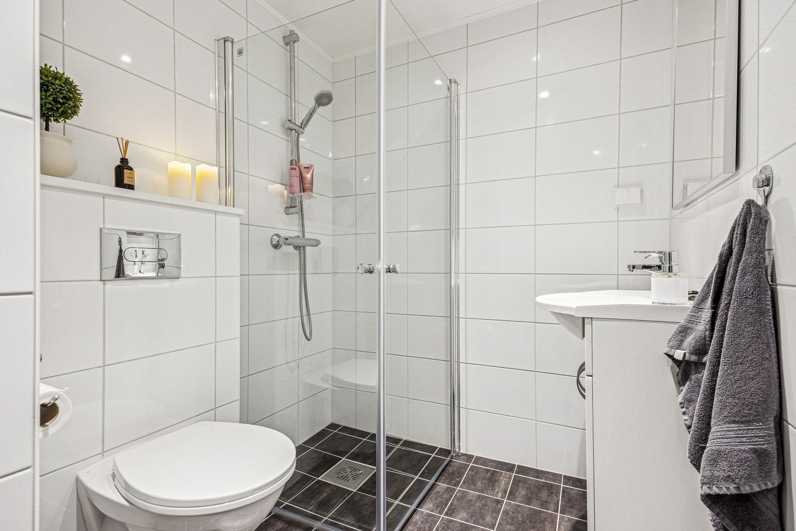 Baderommet i 1. etasje fremstår moderne og funksjonelt, med en praktisk og tidløs utforming som dekker familiens behov. Galleribilde