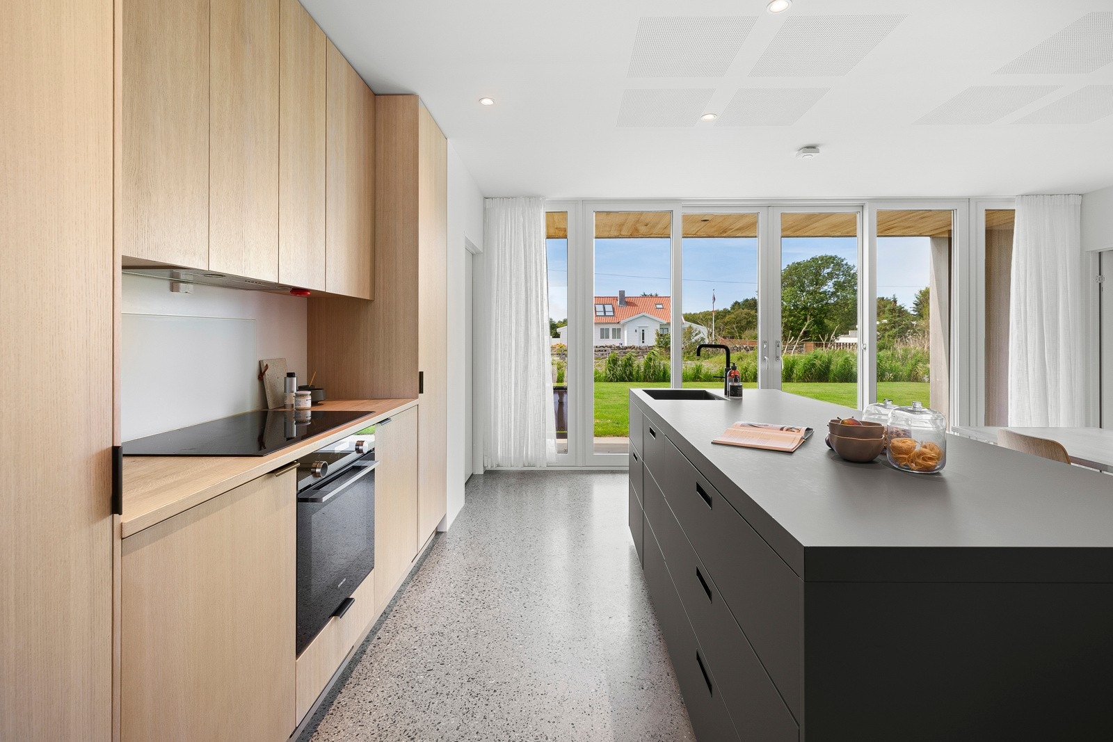 Fra spisekjøkkenet nede er det utgang til terrassen og hagen. Kjøkkenet har pusset betonggulv, lysmalte overflater og downlights. Galleribilde