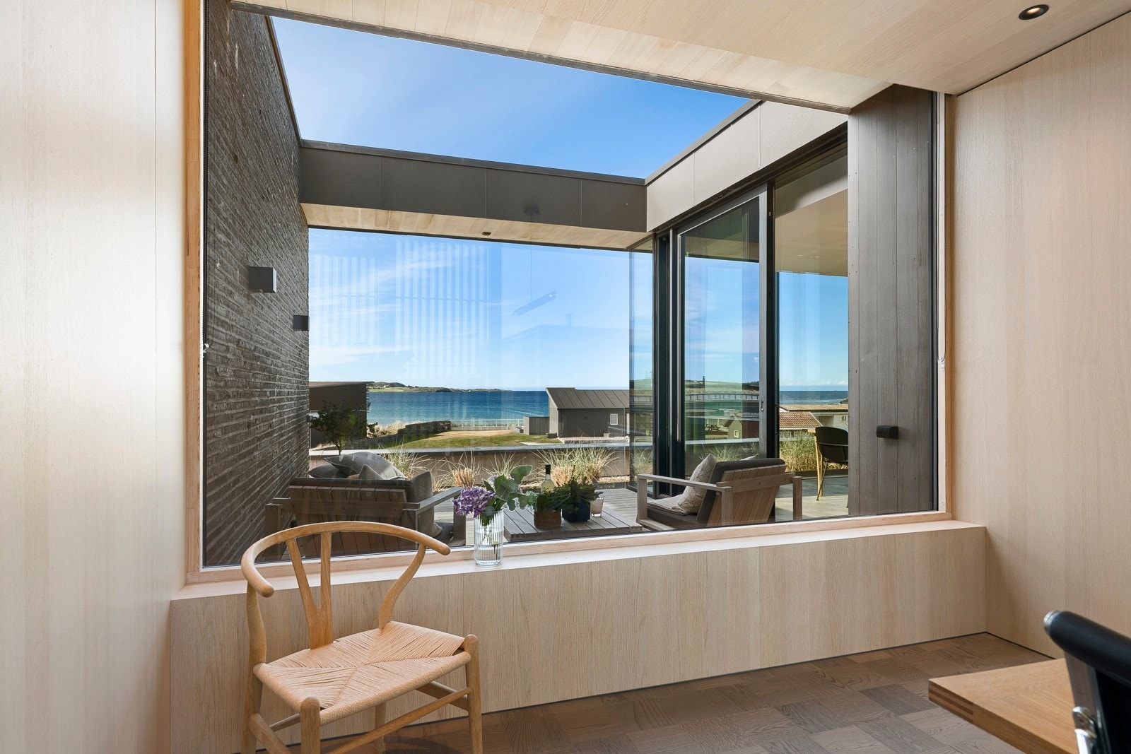 Et stort vindu vender mot garasjetaket i sedum, mens det andre vinduet vender mot balkongen og sjøutsikten. Galleribilde