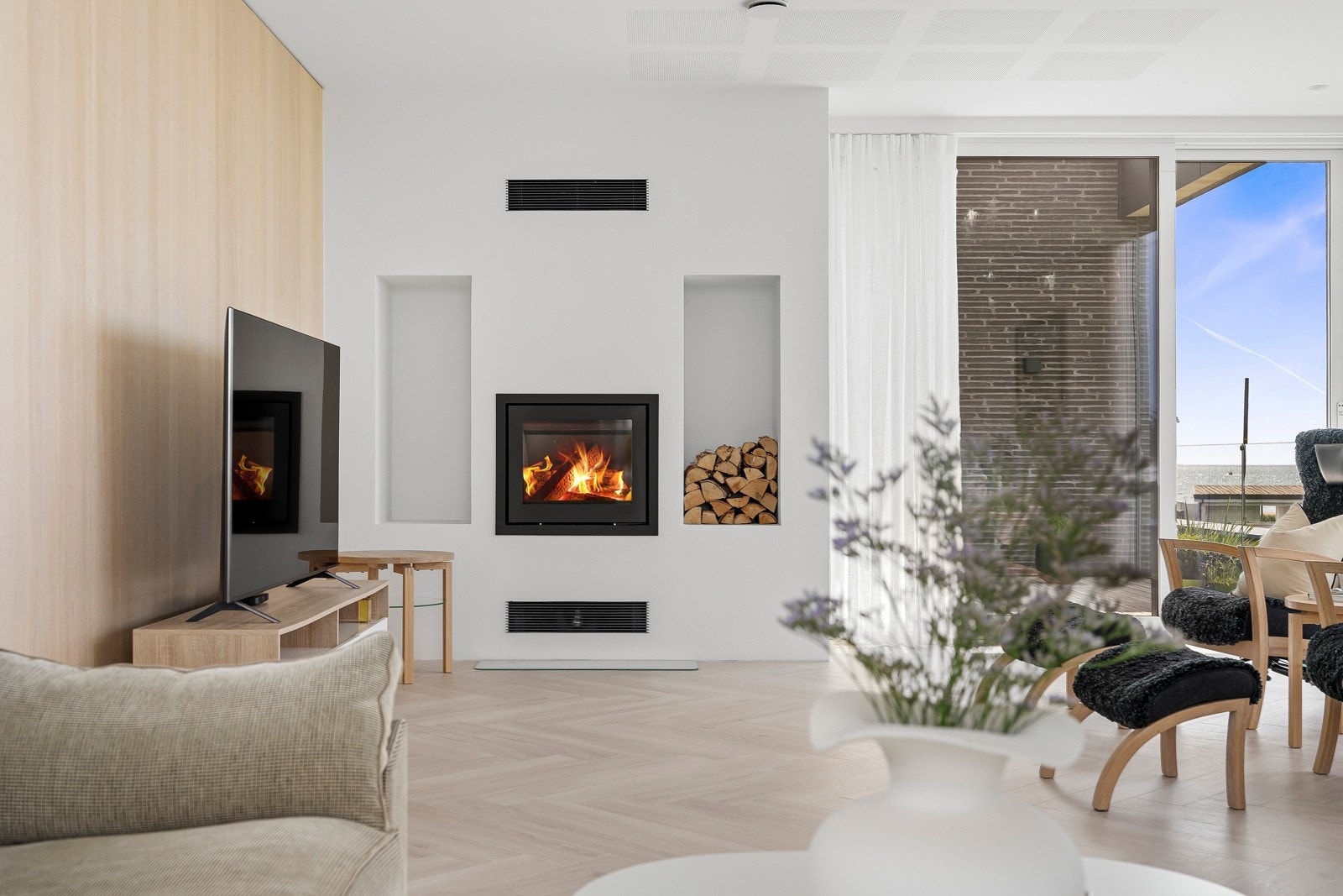 I den ene veggen er det felt inn en flott peis med glassdør og stort flammebilde. Galleribilde