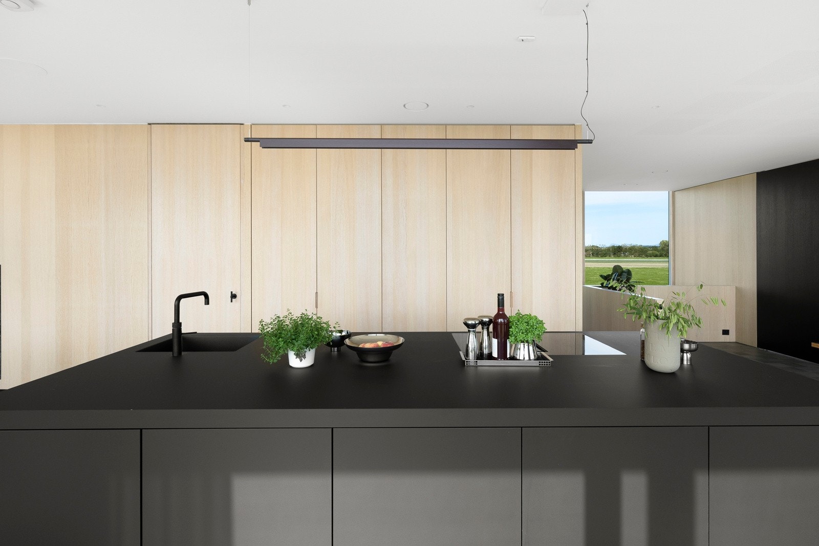 Kjøkkenøya har sorte, matte fronter og matchende benkeplate i laminat med sort vaskekum og Qooker krane/armatur. Galleribilde