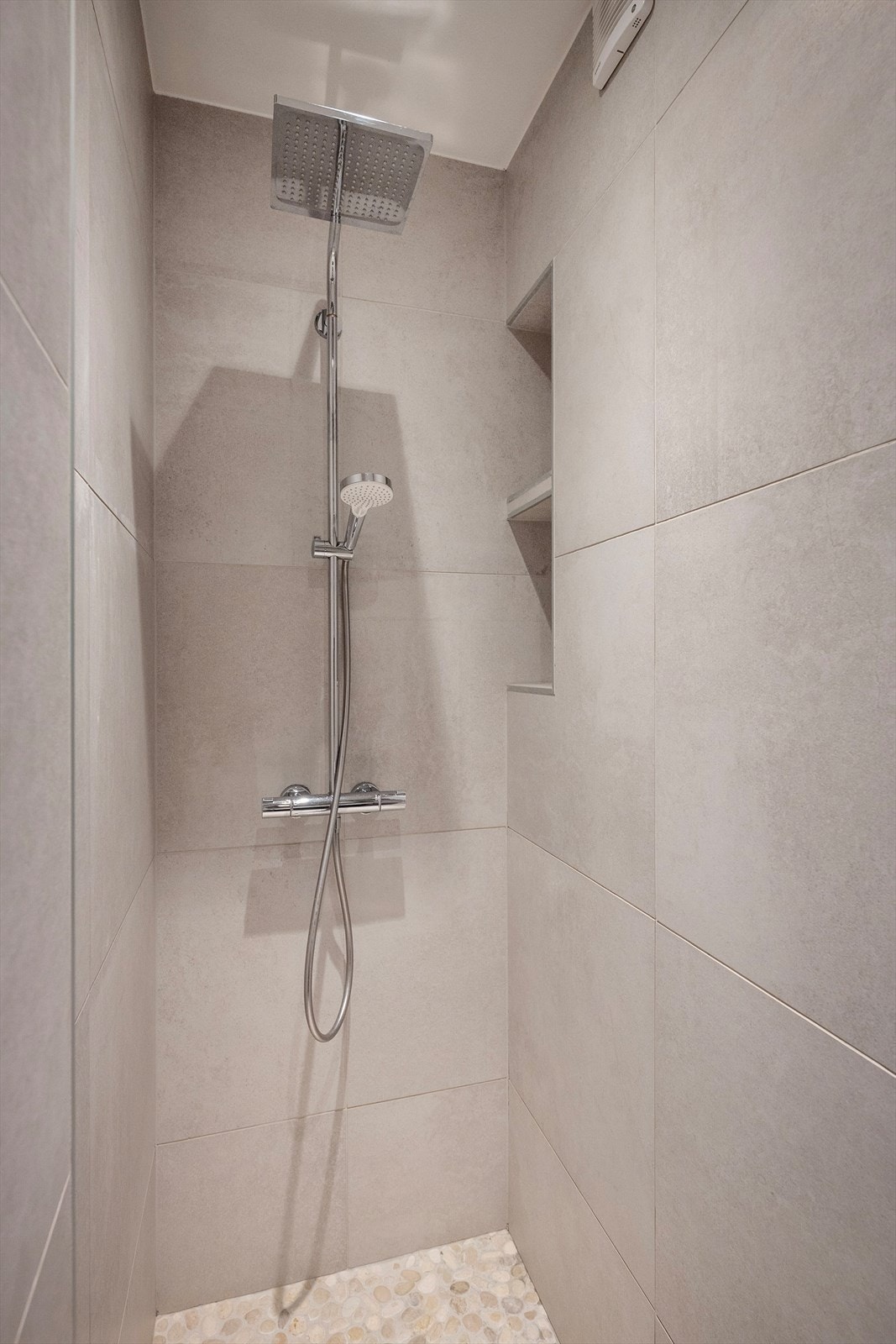 Her er det vegghengt toalett, servant og speilskap og stor dusj med rullestein. Galleribilde