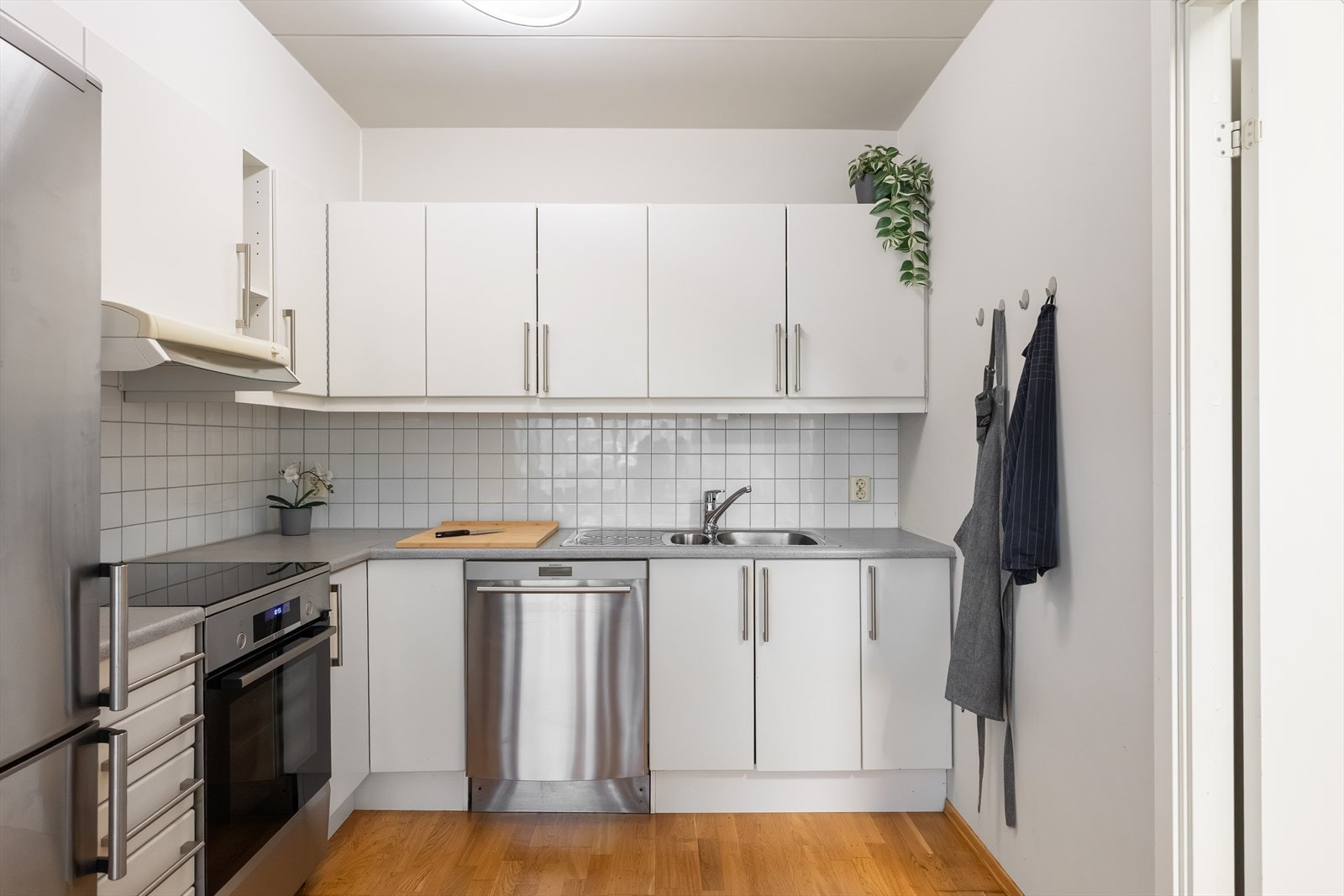 Lyst og flott kjøkken bestående av hvite, glatte fronter og benkeplate av laminat med nedfelt vaskekum. Galleribilde