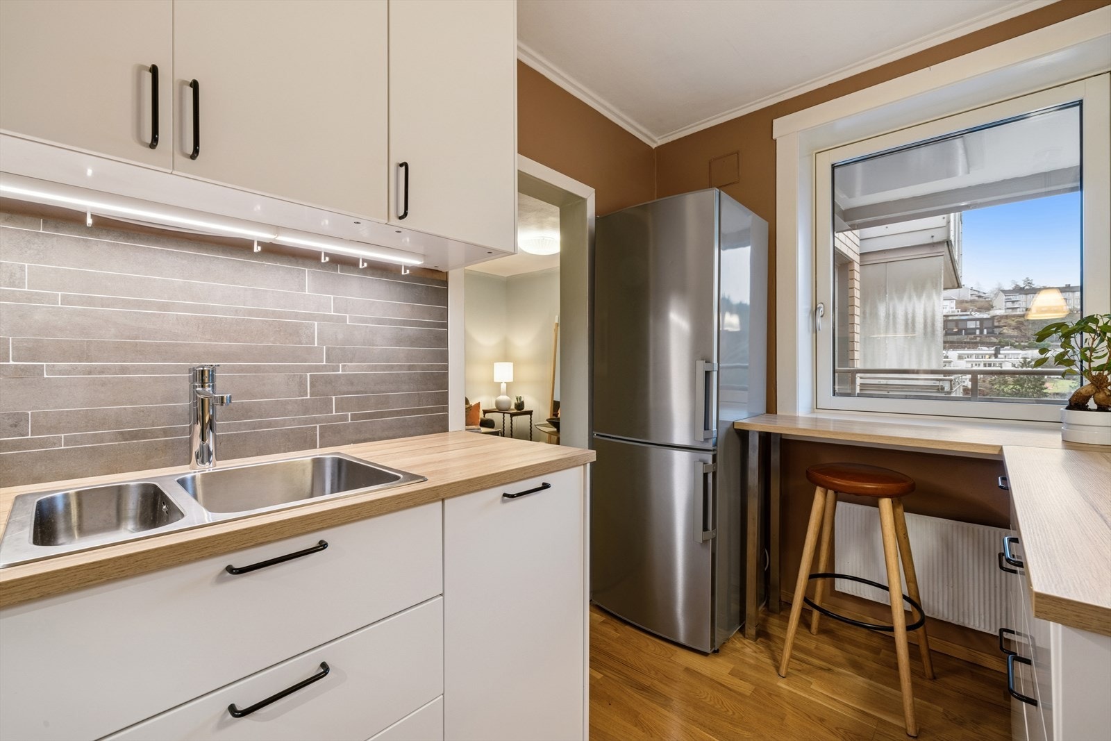 Ventilasjonen består av en kullfilterventilator over kokesonen og en avtrekksventil i overskapet. Et stort vindu slipper inn rikelig med dagslys og rammer inn den flotte utsikten - perfekt for å skape en lys og trivelig atmosfære i hjemmets hjerte. Galleribilde