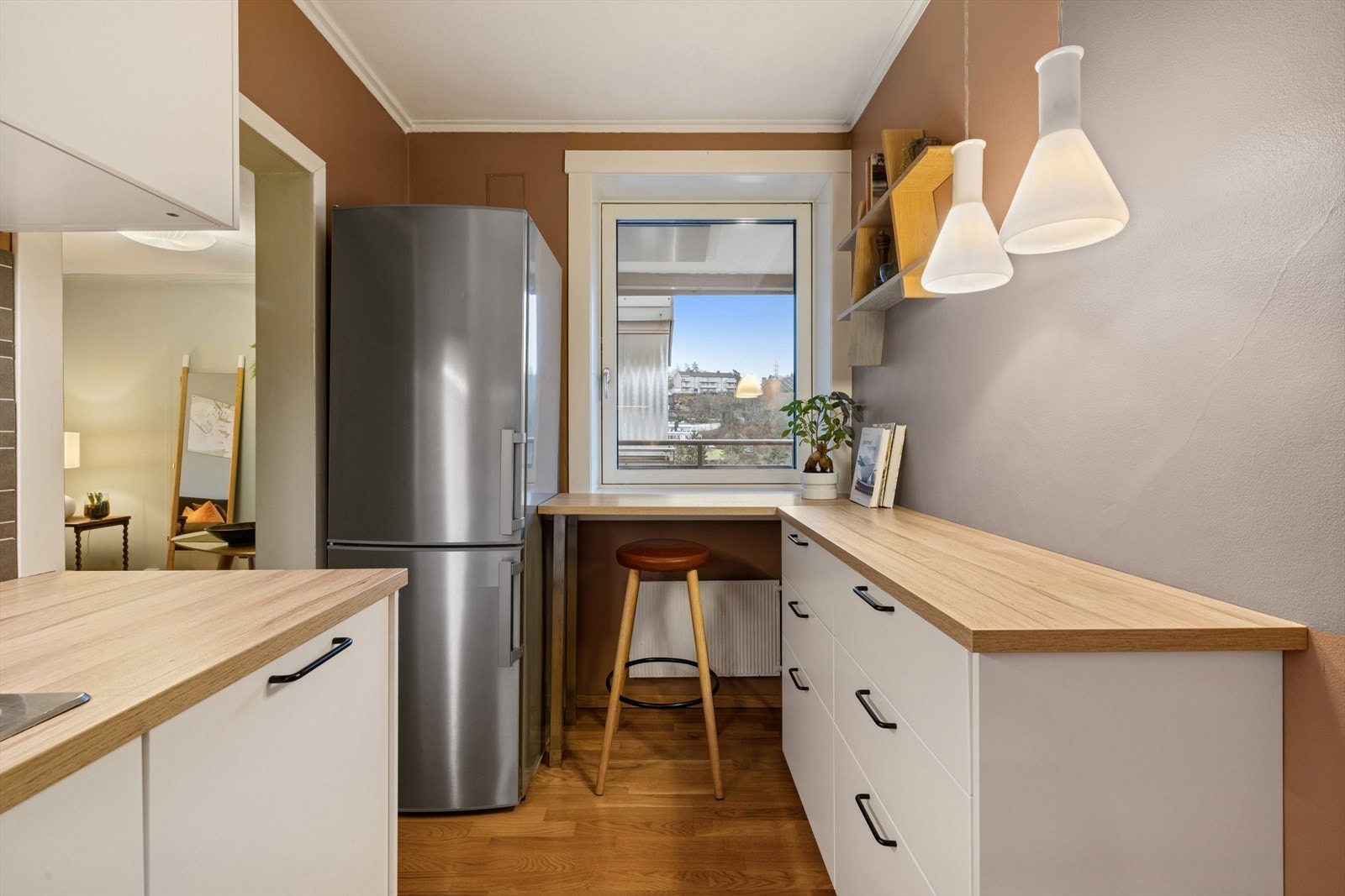 I forlengelsen av arbeidsbenken er det laget en praktisk frokostplass ved vinduet, perfekt for en rask kopp kaffe eller en enkel frokost. Her er det plass til en barstol, slik at du kan nyte måltidene med utsikt og naturlig lys. Galleribilde