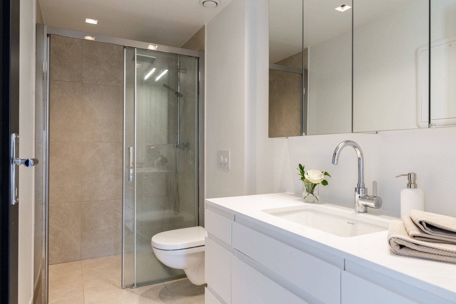 Bad 2 i 2. etasje er innredet med dusjhjørne med glassvegger, vegghengt toalett og servant med moderne innredning og speilskap. Galleribilde