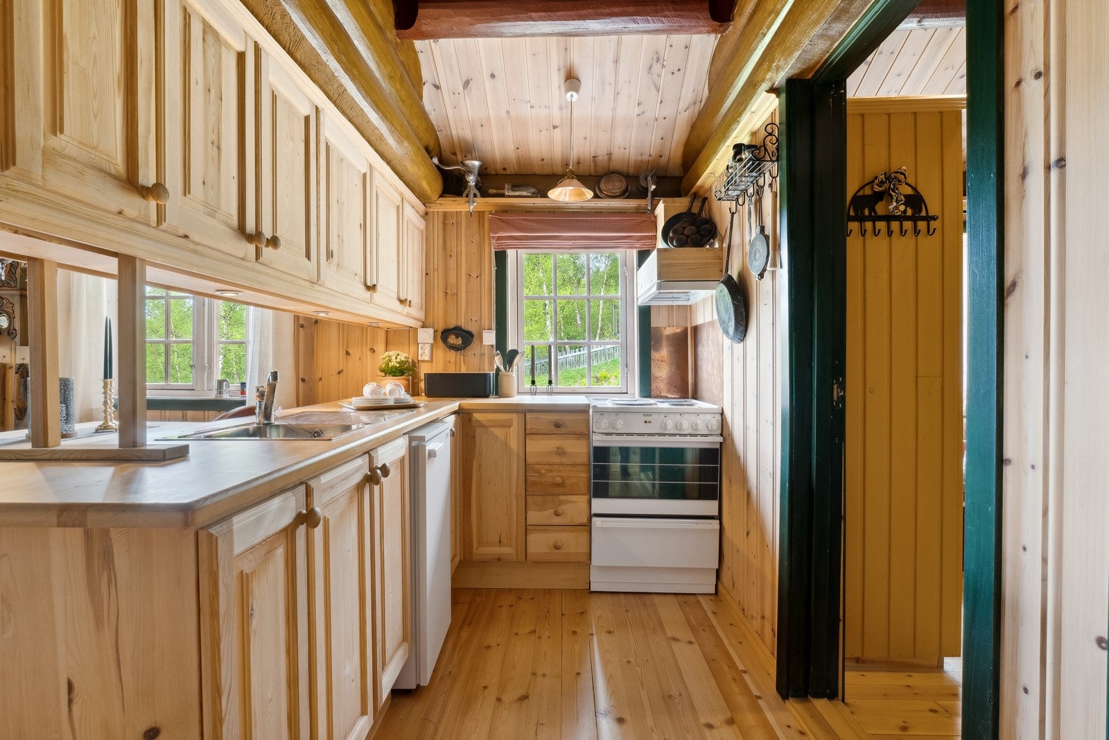 Kjøkkenet i generasjonsdelen har trehvite fronter, benkeplate i heltre, ventilator, komfyr og kjøleskap. Galleribilde