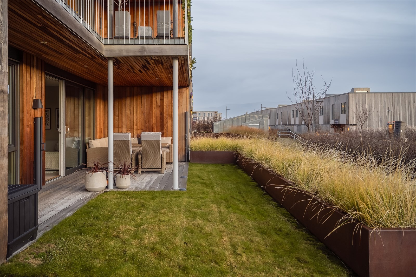 Som en forlengelse av terrassearealet er det pent opparbeidet plen på fellesareal, skjermet for forbipasserende med plantekasser. Galleribilde