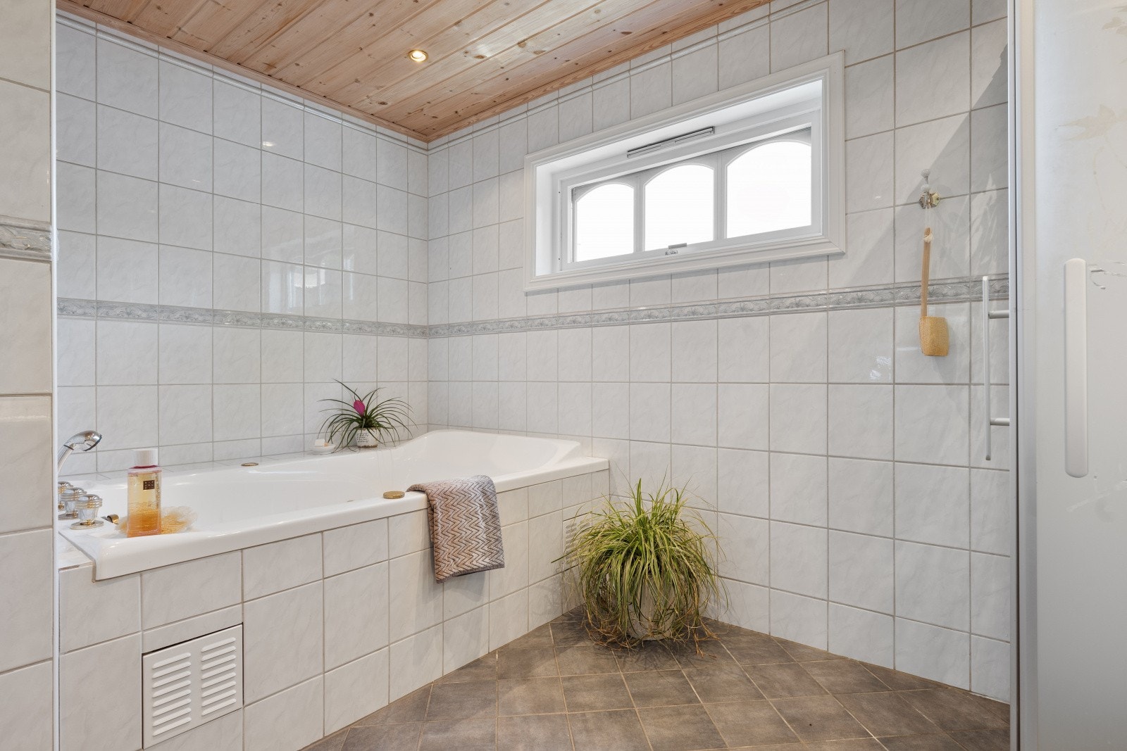 Badet er innredet med badekar, toalett og en praktisk veggseksjon med servant. Galleribilde