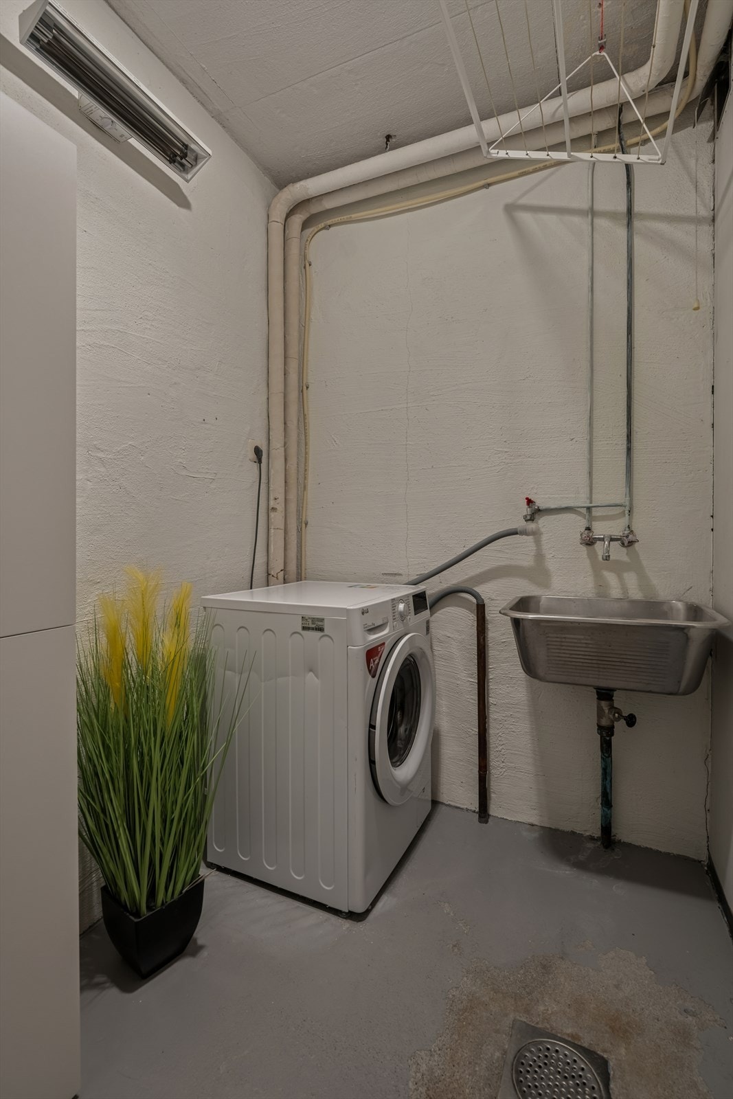 Vaskerommet har malt betonggulv og vegger med slette plater, samt opplegg for vaskemaskin og skyllekar. Naturlig avtrekk gjennom veggventil sikrer ventilasjon. Galleribilde