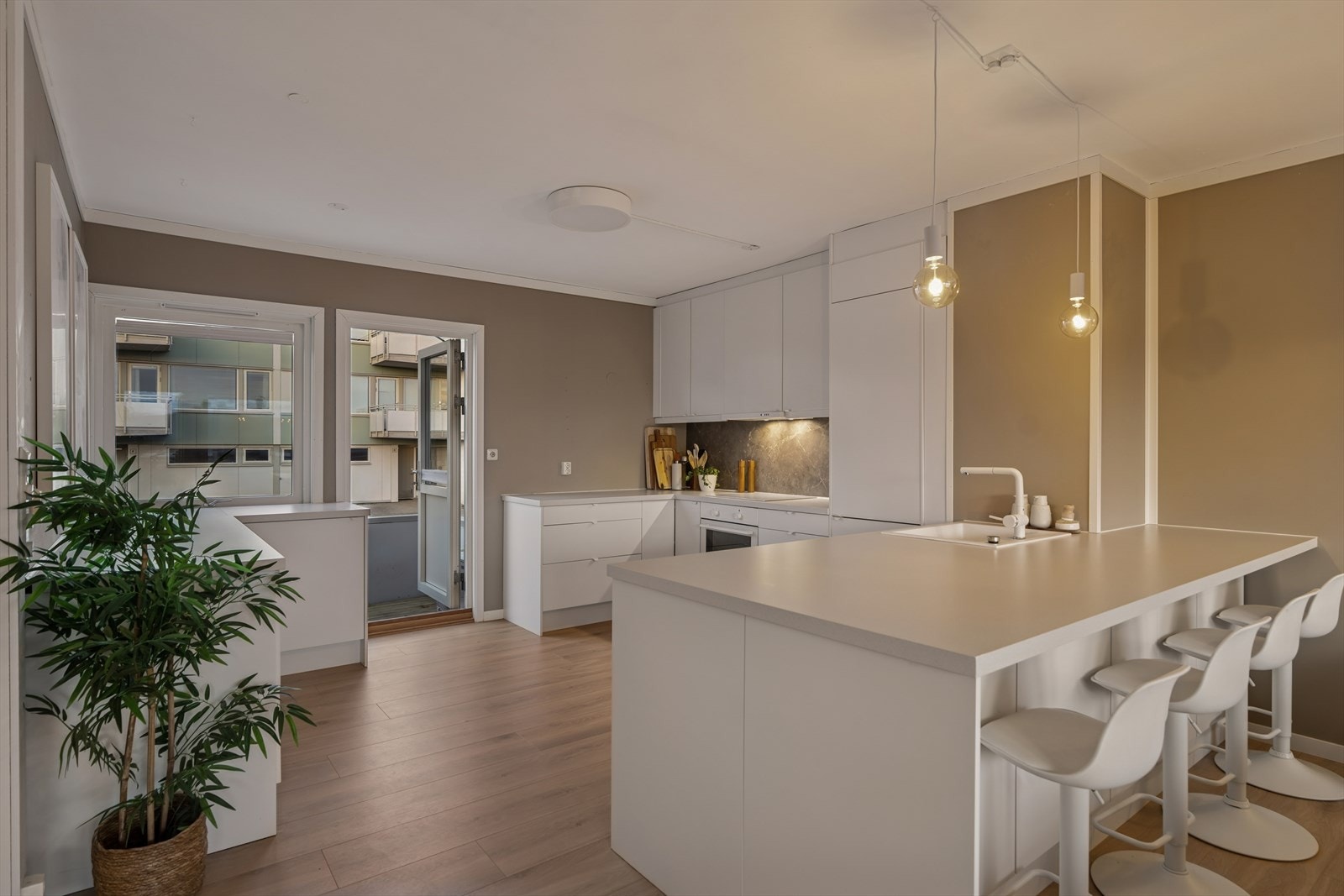 Kjøkkenet har en åpen planløsning med integrerte hvitevarer og benkeplate i laminat. Utgang til uteplass også fra kjøkkenet. Galleribilde