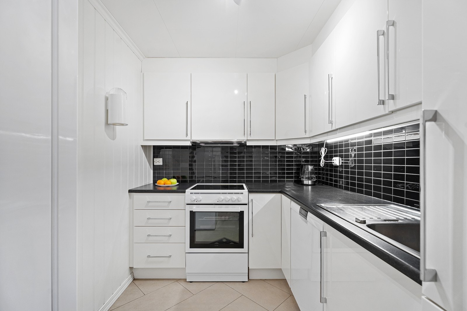 Tidløst kjøkken med hvite fronter og mørk benkeplate. Galleribilde