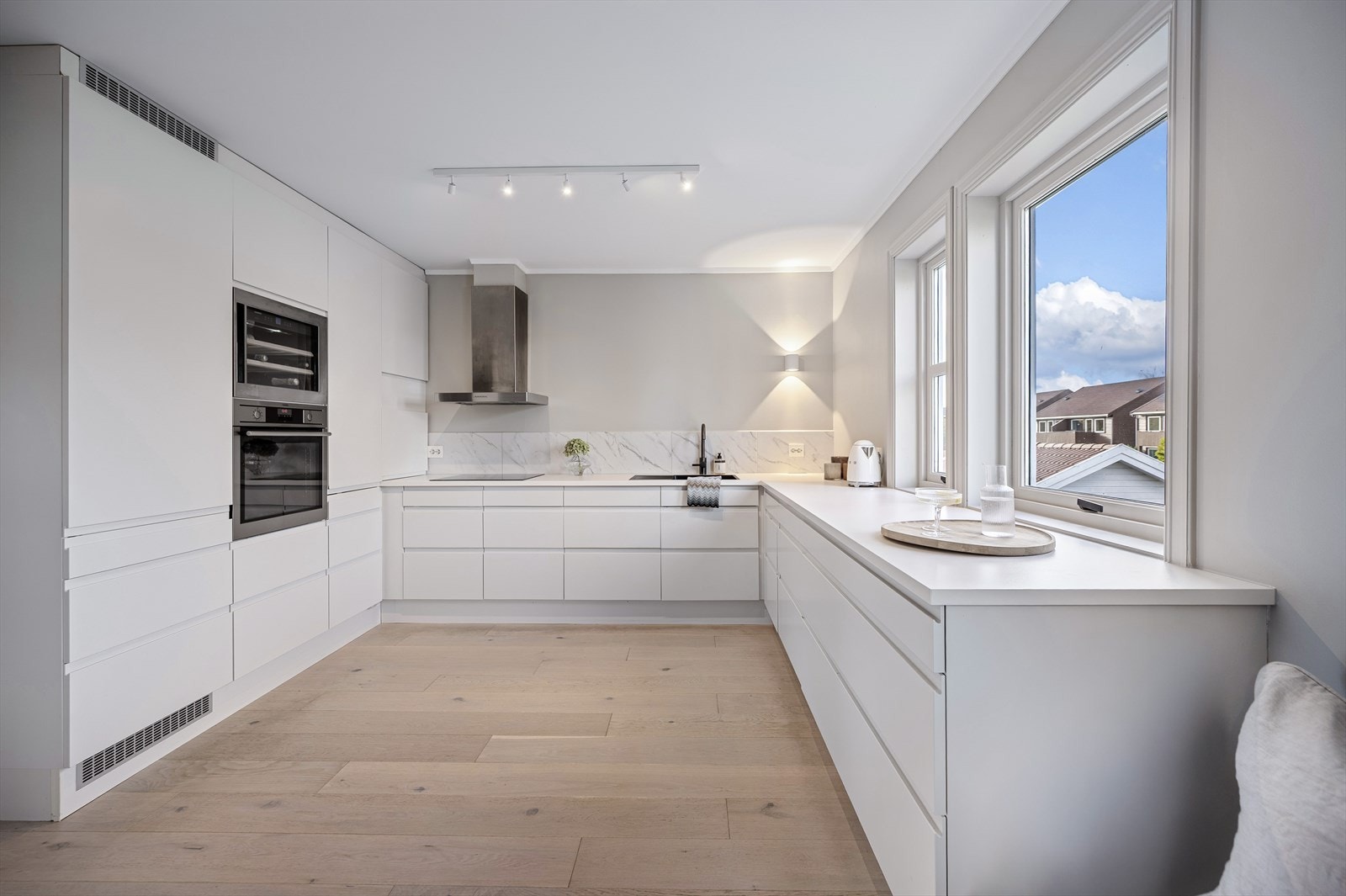 Svært og tidløst kjøkken med hvite fronter og benkeplate Galleribilde