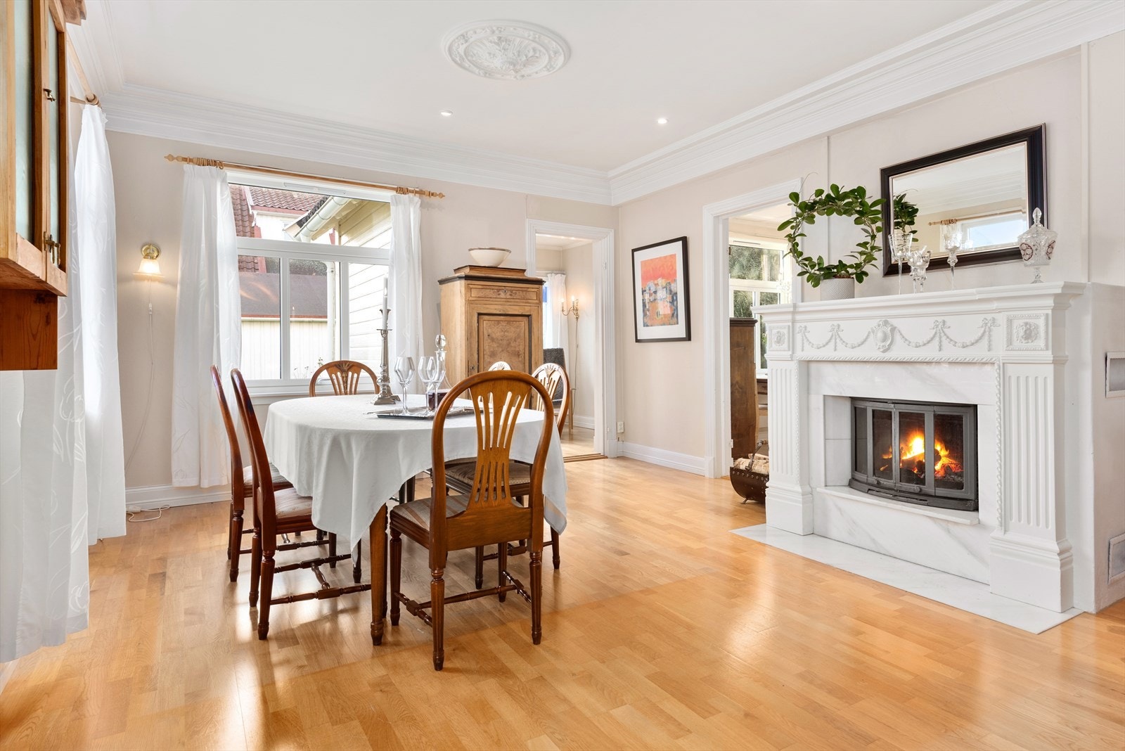 Stuen fremstår med klassiske detaljer, herunder takrosett i himlingen og en flott peis sentralt plassert. Galleribilde