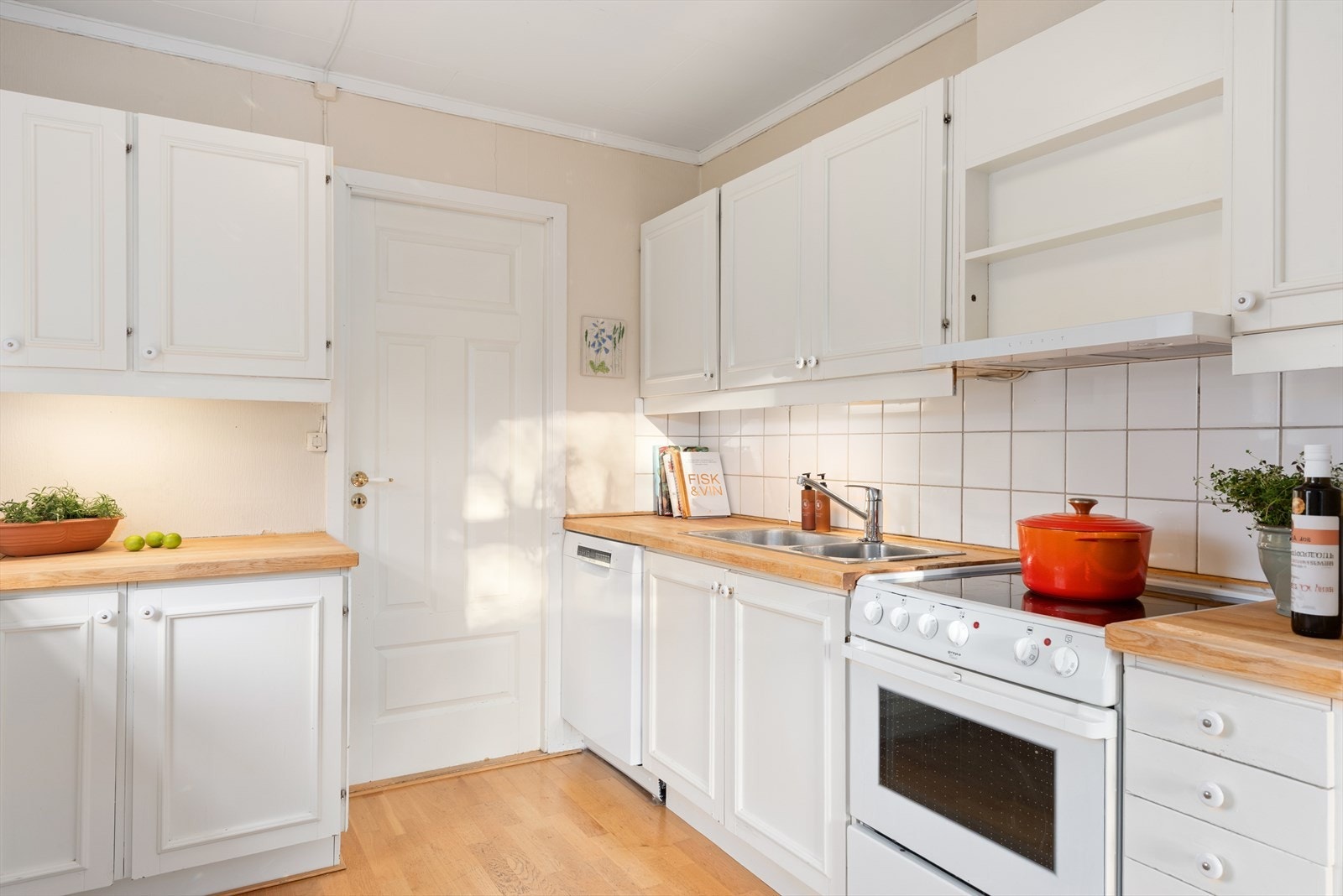 Innredningen har et lyst og klassisk uttrykk, med profilerte fronter av ukjent alder. Heltre benkeplate er kombinert med nedfelt kum og blandebatteri i rustfritt stål, og veggene over benk og platetopp er flislagt. Galleribilde