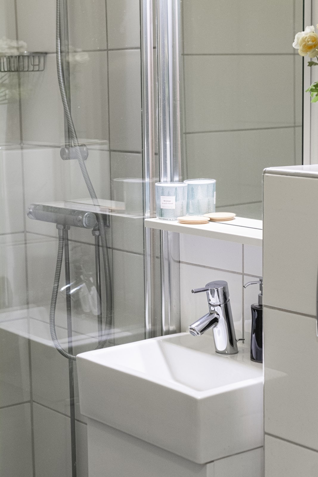 Baderomsinnredning bestående av benkeskap med glatte fronter, servant, speil og integrert belysning, dusjhjørne med faste glassfelt og dør i herdet glass. Det er vegghengt toalett med innebygd sisterne. Galleribilde