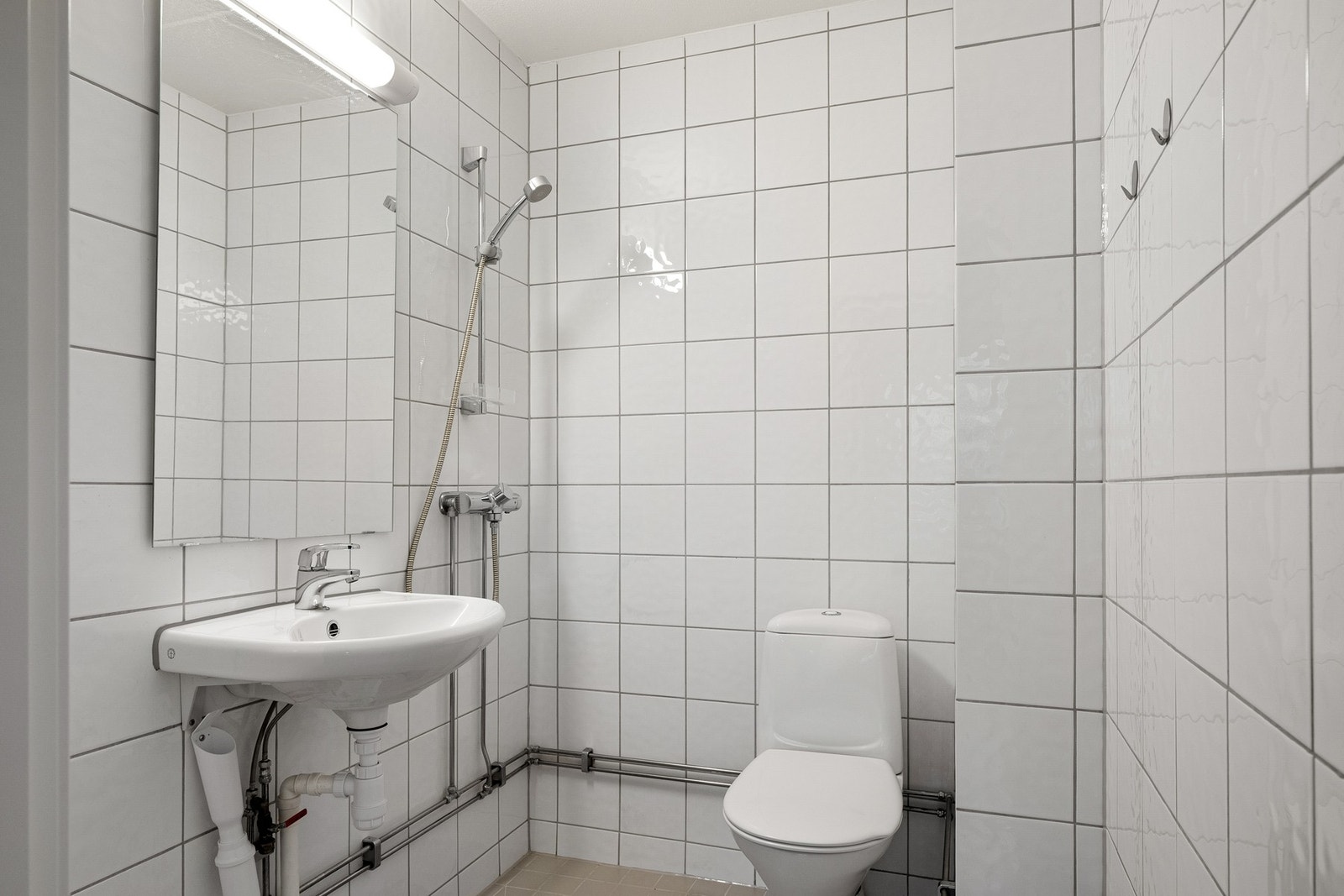 Flislagt bad med dusj, wc, servant og opplegg for vaskemaskin. Galleribilde