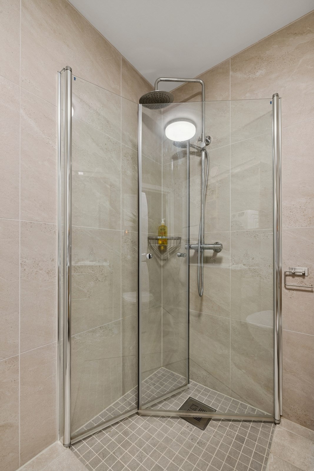 Moderne dusjhjørne fra 2021 med glassvegger, flislagte overflater og stilrent armatur. Galleribilde