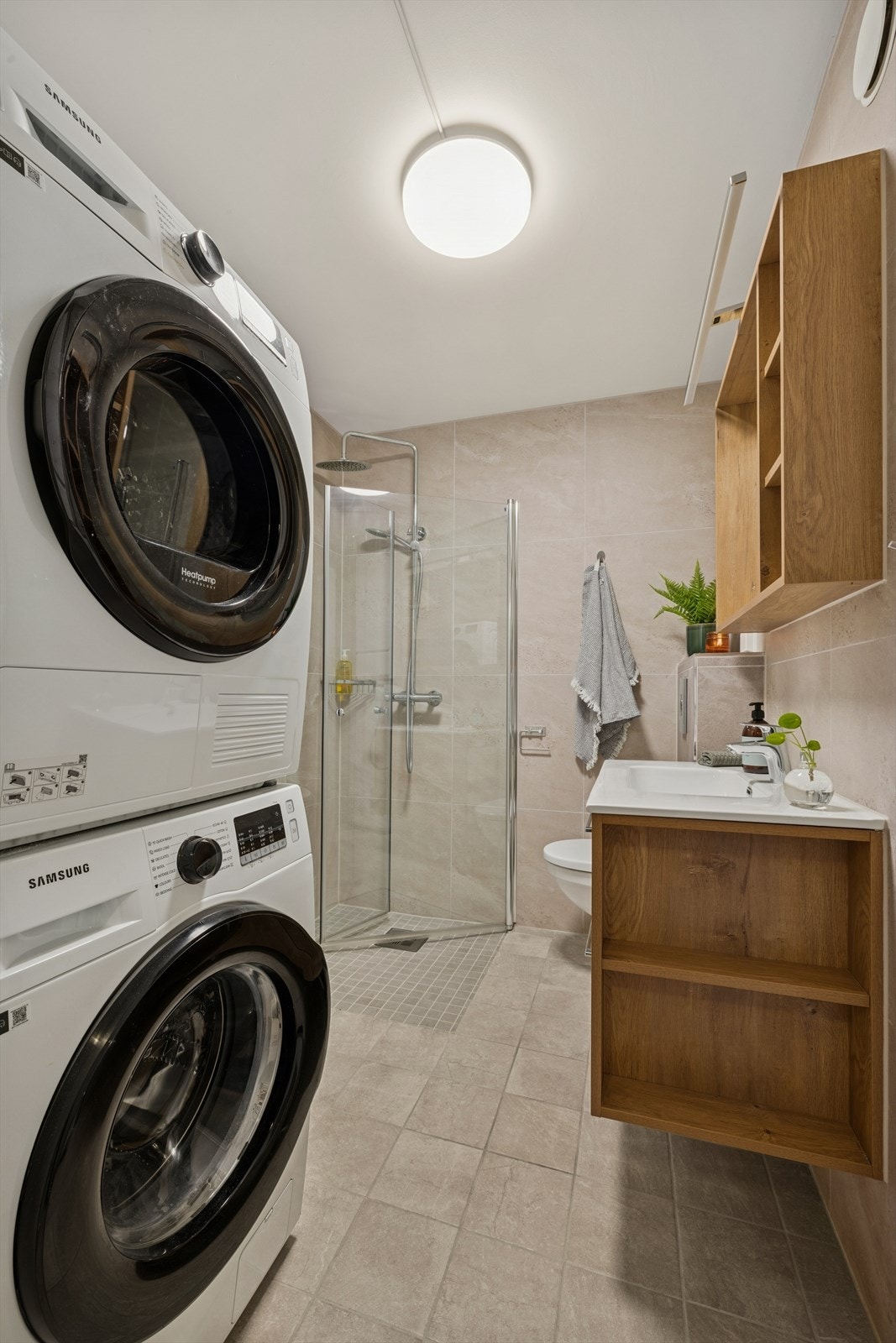 Badet er innredet med servantskap med ett-greps blandebatteri, speilskap, veggskap, vegghengt toalett med innebygget sisterne, avskjermet dusjhjørne med glass, blandebatteri og dusjgarnityr. Galleribilde