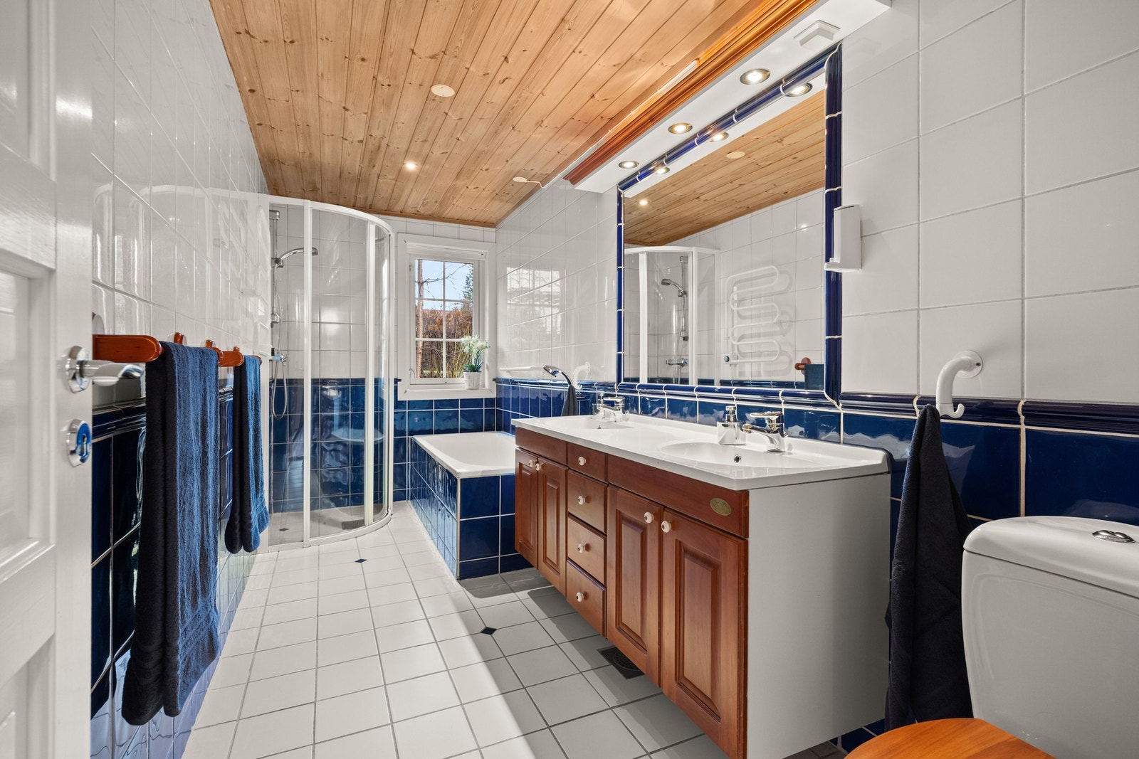 Flislagt bad i 1. etasje med varmekabler, utstyrt med dobbel servantseksjon med skuffer og skap, samt speil. Galleribilde