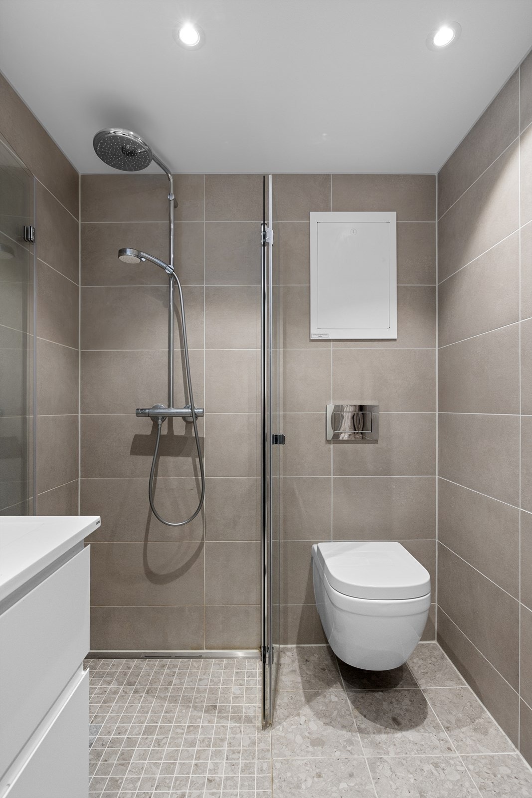 Innredningen består av dusjhjørne med svingbare glassdører i herdet glass, vegghengt klosett og servant med underskap og belysning. Galleribilde