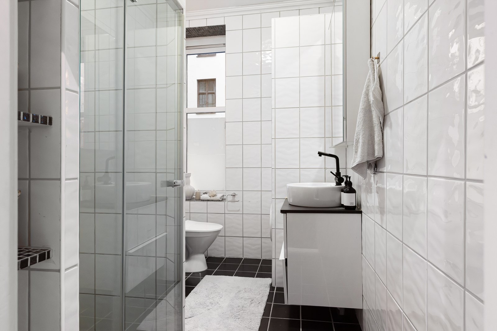 Pent flislagt bad med elektrisk gulvvarme. Det er innredet med servant, speilskap, toalett og dusjsone med svingbare glassdører. Galleribilde