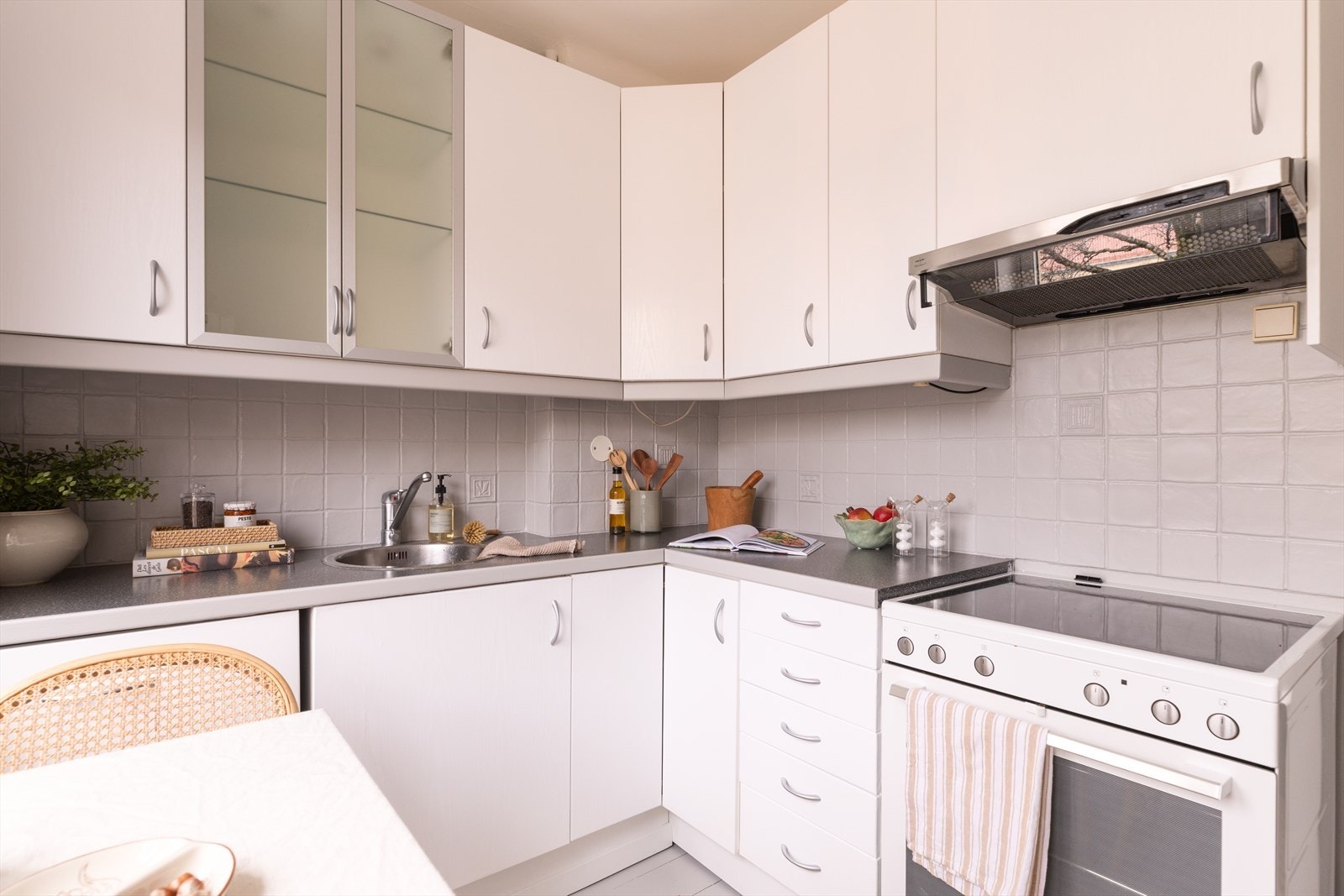 Innredningen har folierte fronter, laminat benkeplate og malte fliser over benken. Kjøkkenet er utstyrt med frittstående komfyr, integrert oppvaskmaskin og en avtrekksvifte med omluft (kullfilter). Galleribilde