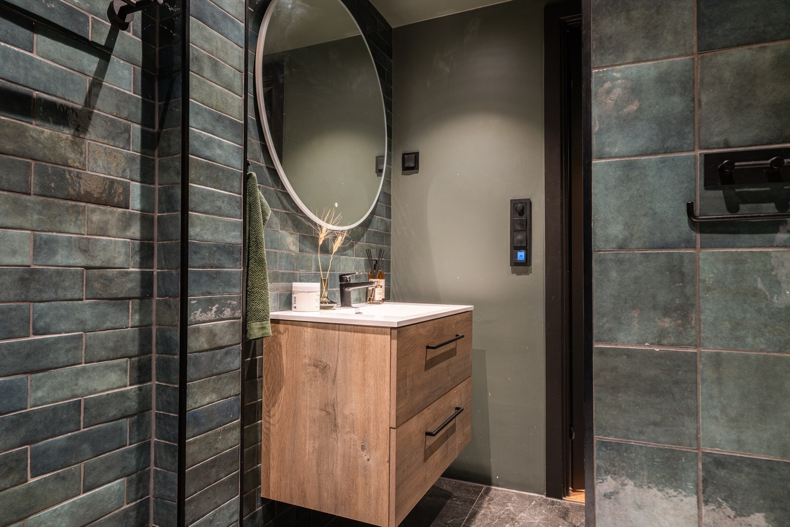 Servantinnredning med stort rundt speil over - Sorte detaljer med brytere, håndtak og håndkletørker Galleribilde