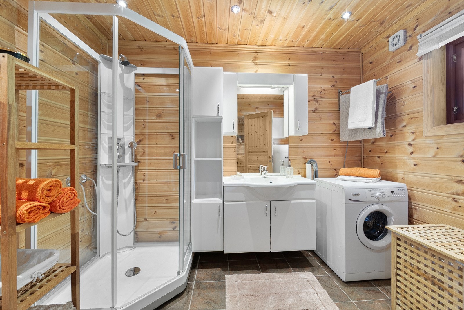 Et flott hyttebad som er innredet med servant nedfelt i baderomsinnredning, toalett, dusjkabinett og opplegg for vaskemaskin. Galleribilde