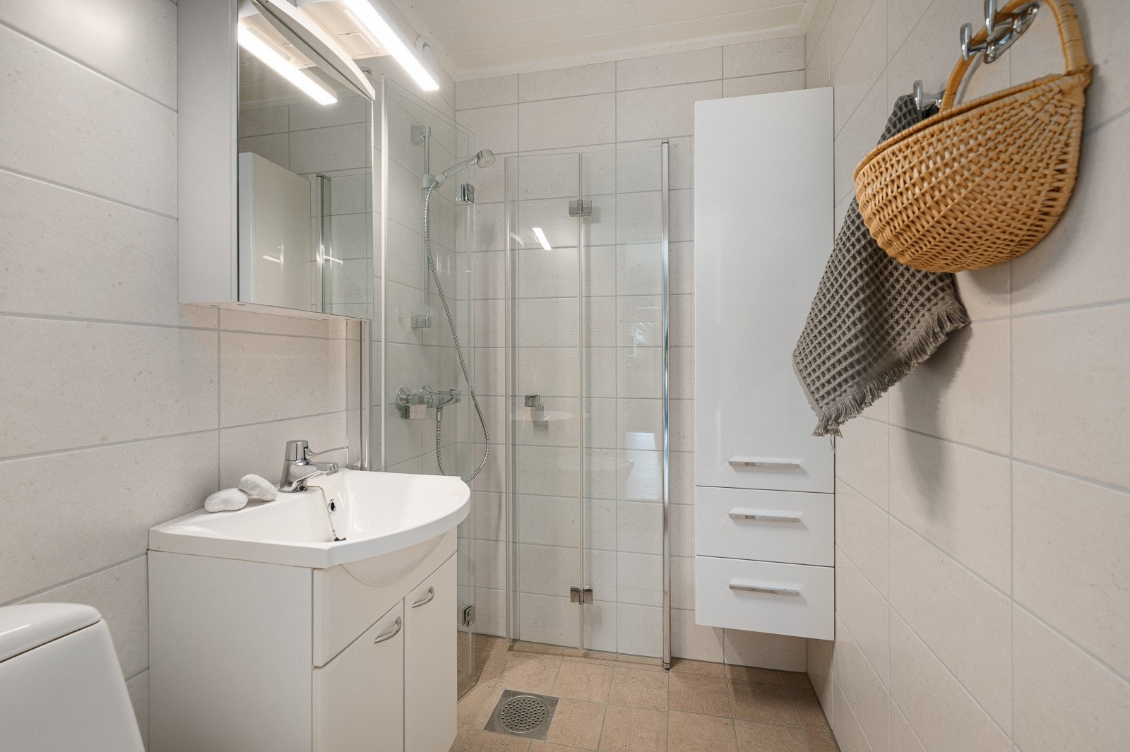 Badet med adkomst fra stue/kjøkken ble renovert i 2025 - Det er flislagte overflater og varmekabler i gulvet - Rommet har dusjhjørne m/innfellbare glassvegger, baderomsinnredning og toalett Galleribilde