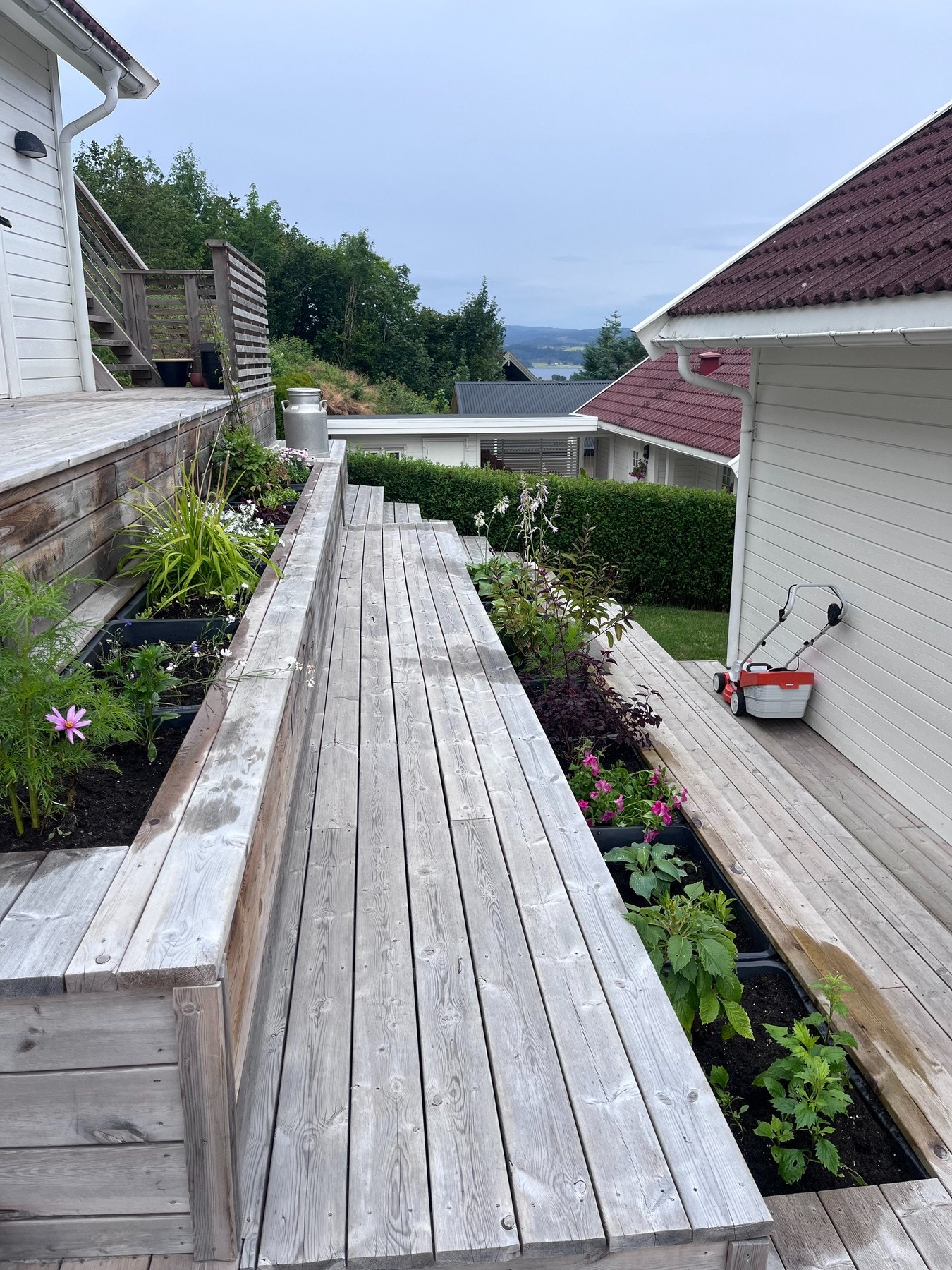 Selgers bilde av tilpasset blomsterbed bak huset mot garasjen. Galleribilde