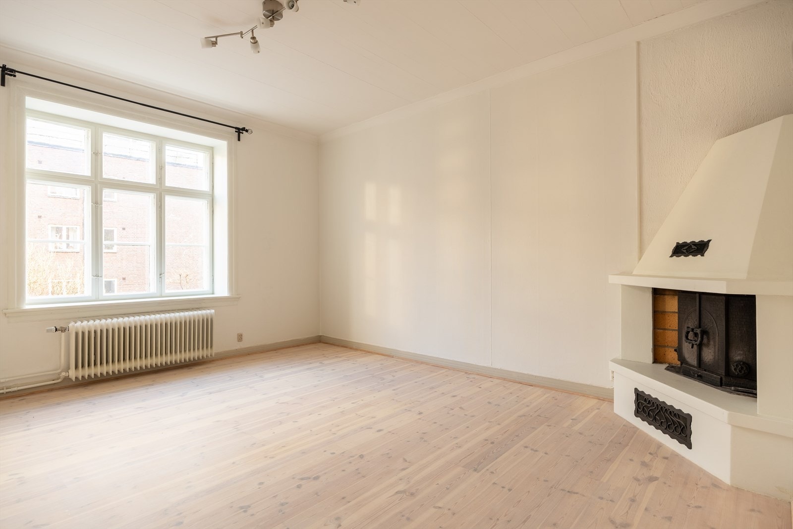 Lys og romslig stue med store vindusflater. Peisovn Galleribilde