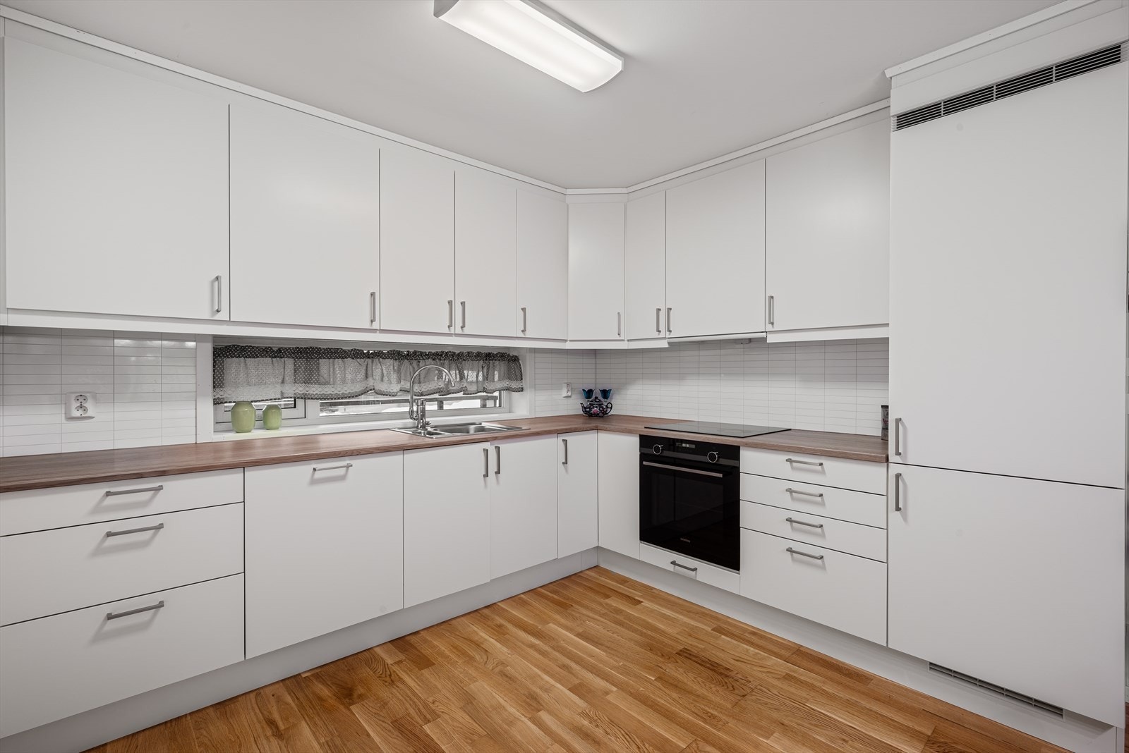 Innredning med nedfelt induksjonstopp og integrert kjøl/fryseskap, stekeovn og oppvaskmaskin som medfølger i handelen. Galleribilde