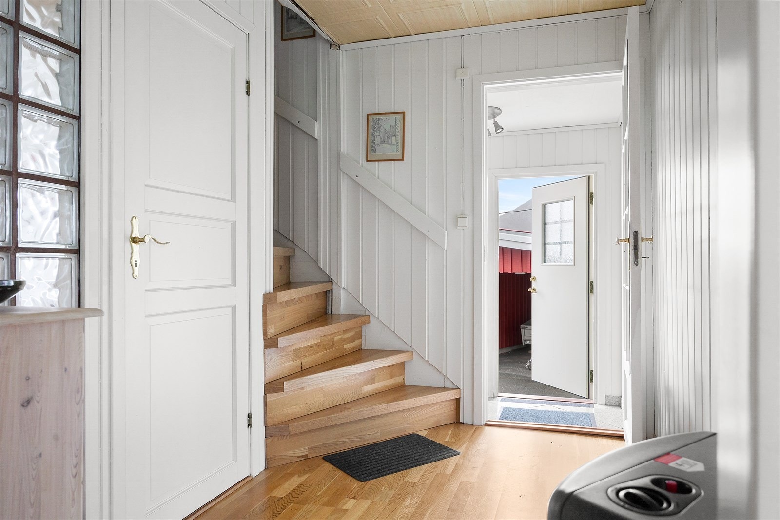 Lys og innbydende entré med flislagt gulv som både er praktisk og lett å holde rent. Fra entréen kommer du inn i gangen, hvor du har tilgang til trappen som leder opp til andre etasje. Galleribilde