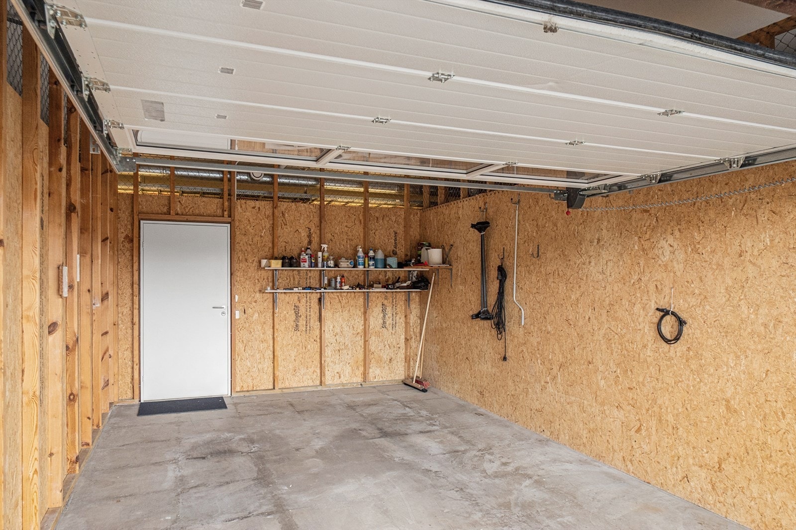 Garasjen har lagringsplass og dør til fellesområdet. Her er også strømuttak. Galleribilde