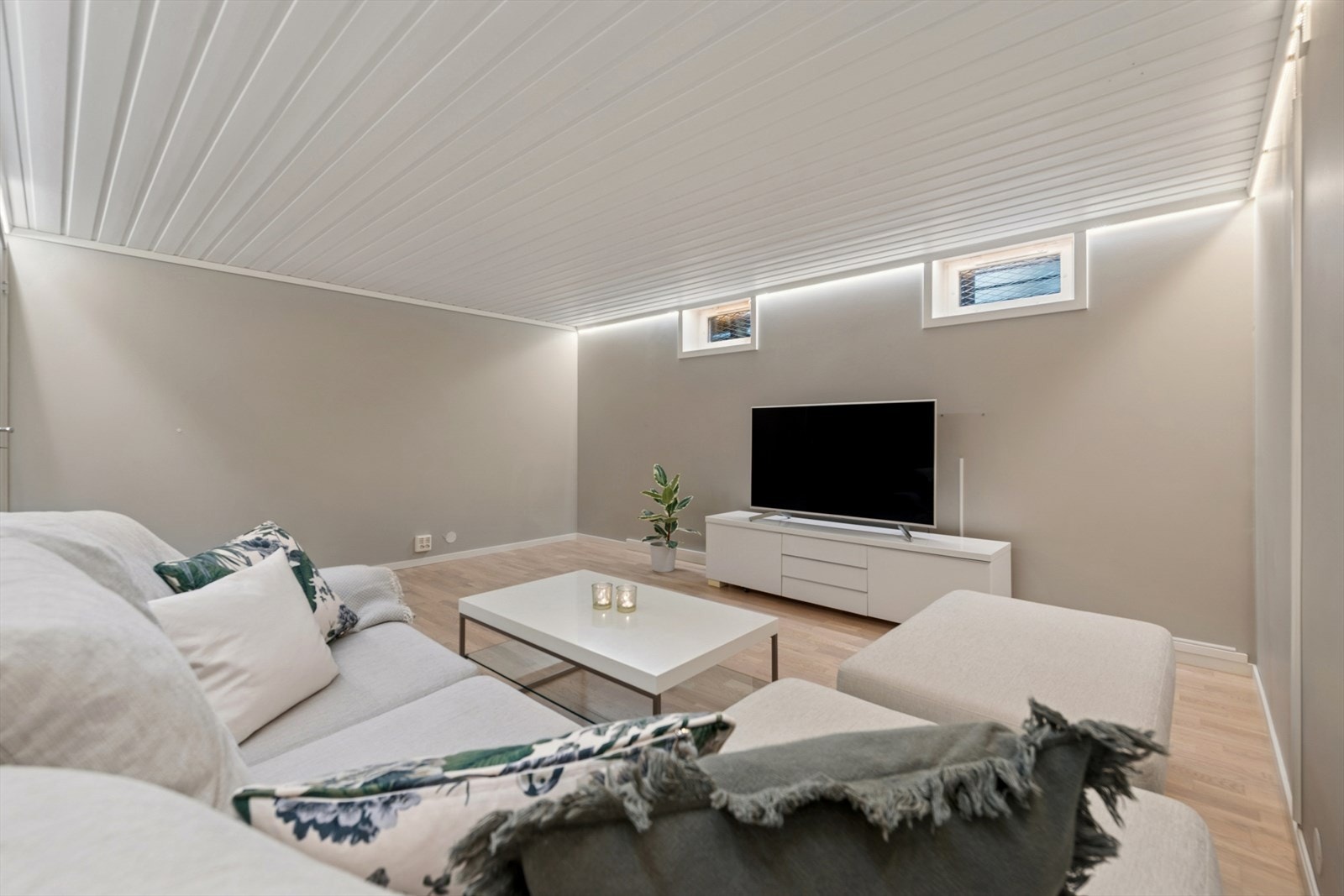 Romslig kjellerstue med gulvvarme, perfekt som TV-stue, lekerom eller et tilbaketrukket oppholdsrom for ungdom i husstanden. Rommet er innredet, men ikke godkjent for varig opphold. Galleribilde