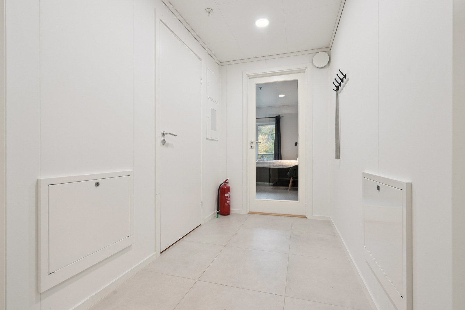 Flislagt gang/entrè med glassdør inn til oppholdsrom/soverom. Galleribilde