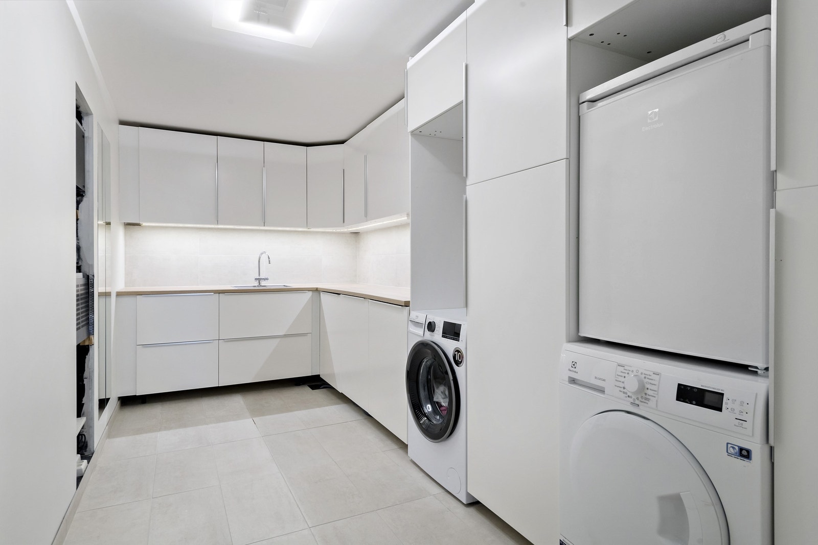 Praktisk innredet vaskerom med mye skuffer og skap til oppbevaring Galleribilde