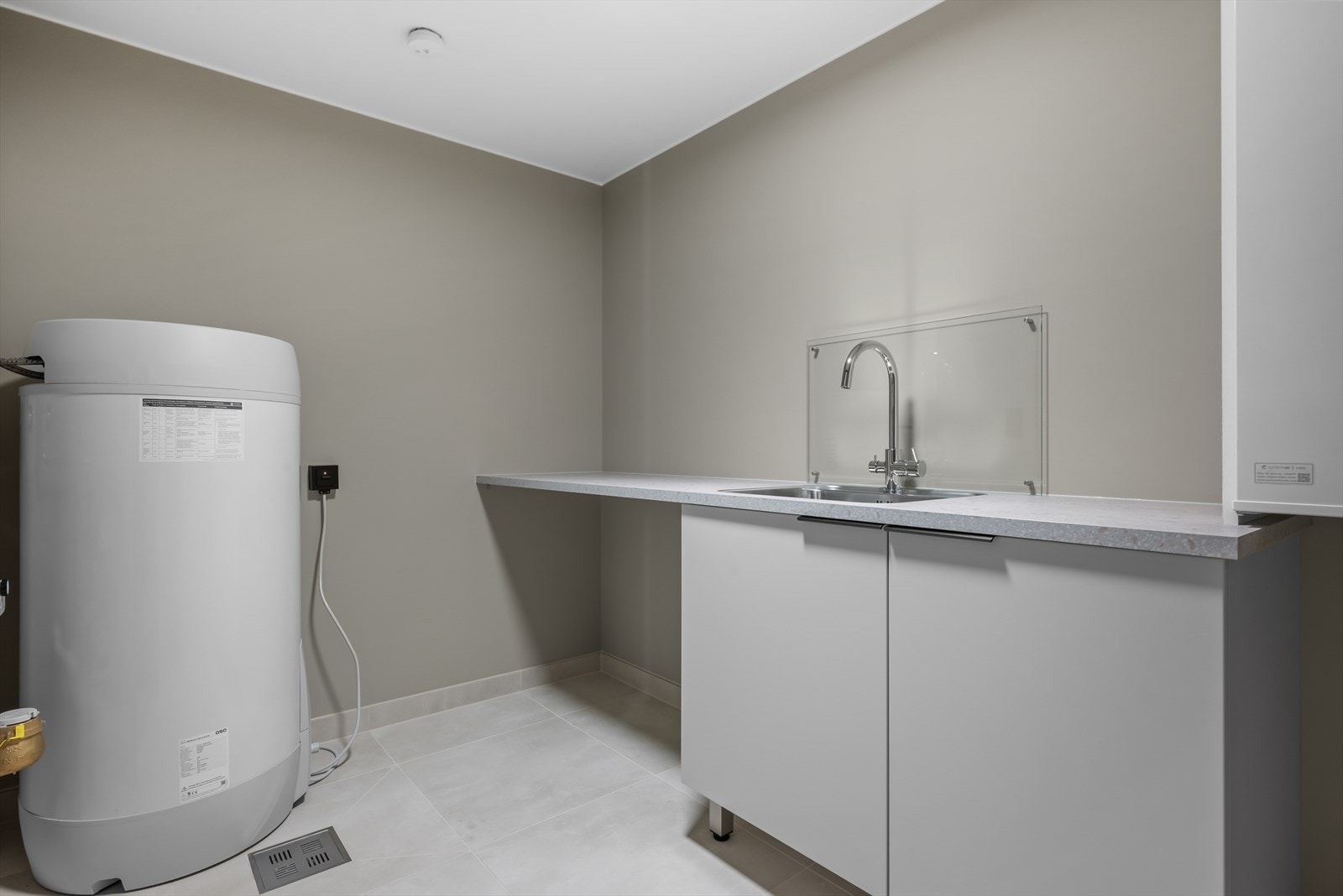 Vaskerom i tilknytning til bad, utstyrt med opplegg for vaskemaskin, innredning med nedfelt vask, varmtvannsbereder og ventilasjonsaggregat. Gulvvarme og mekanisk avtrekk. Galleribilde