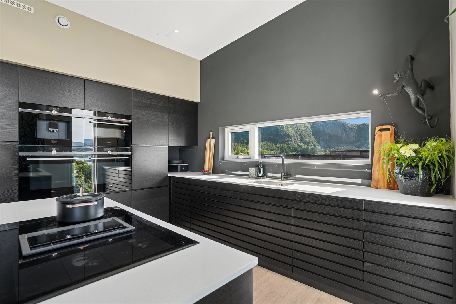 Moderne og gjennomført kjøkkenløsning med god skapplass, integrerte hvitevarer og ventilator i platetopp Galleribilde