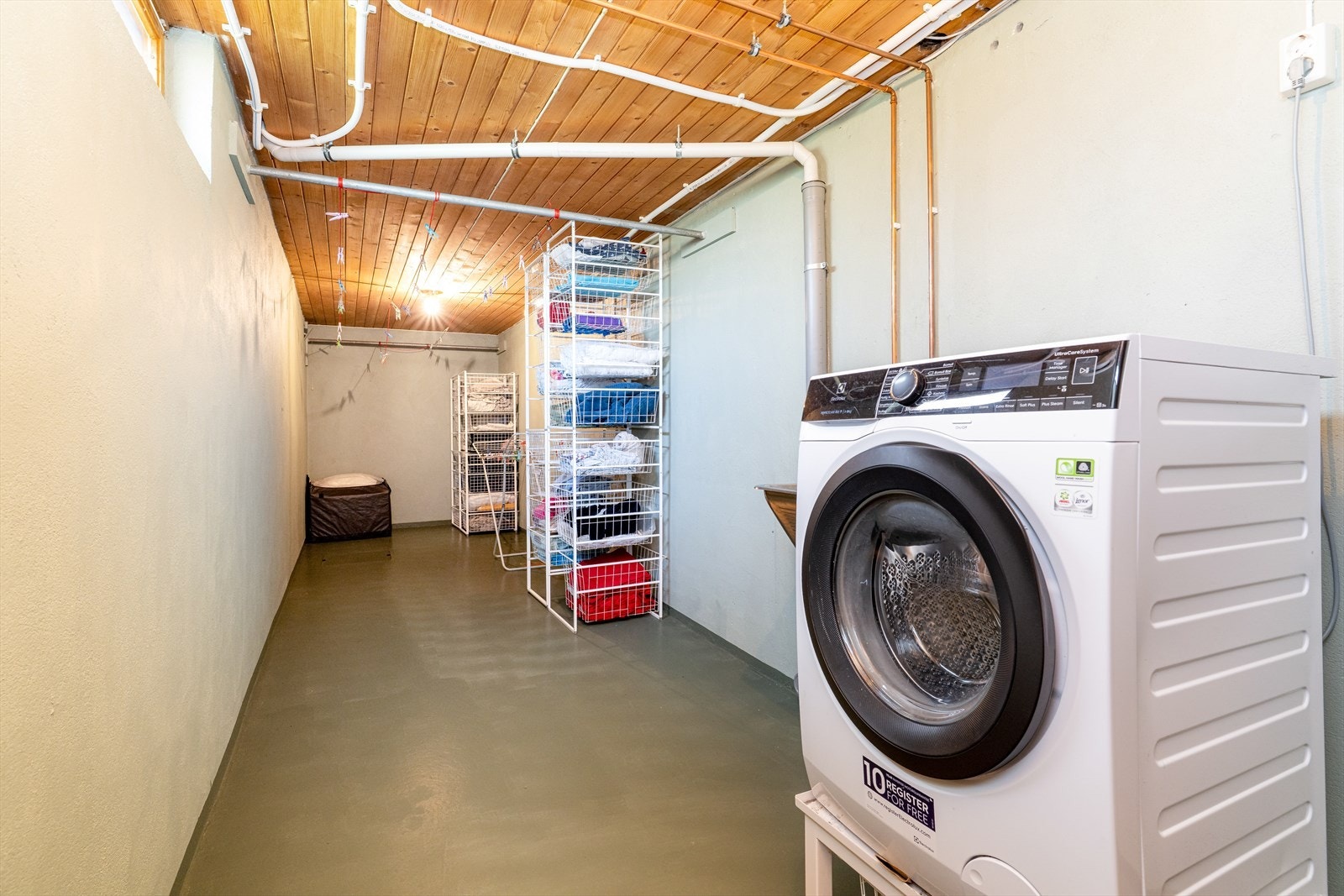 Romslig vaskerom i kjeller med opplegg til vaskemaskin og utslagsvask i stål. Galleribilde