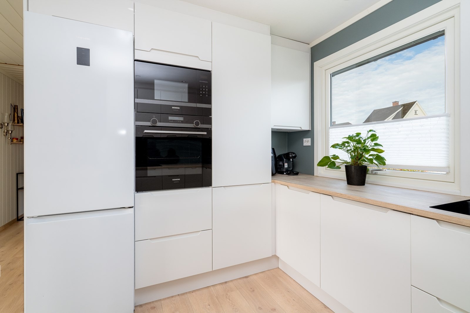 Innredningen består av hvite slette fronter og laminert benkeplate med nedfelt vask i kompositt med ett-greps blandebatteri. Galleribilde