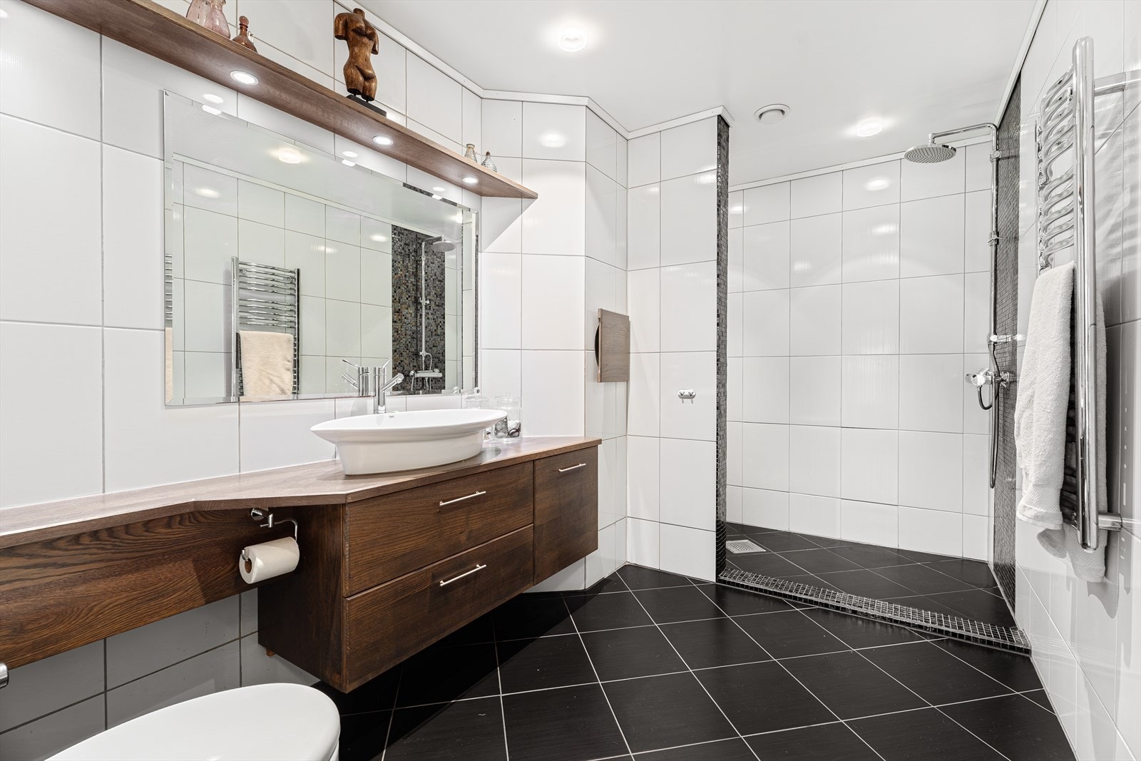 Flott bad i 2. etasje med fliser på gulv m/varme. Åpen dusjnisje, innredning med servant og vegghengt toalett. Galleribilde