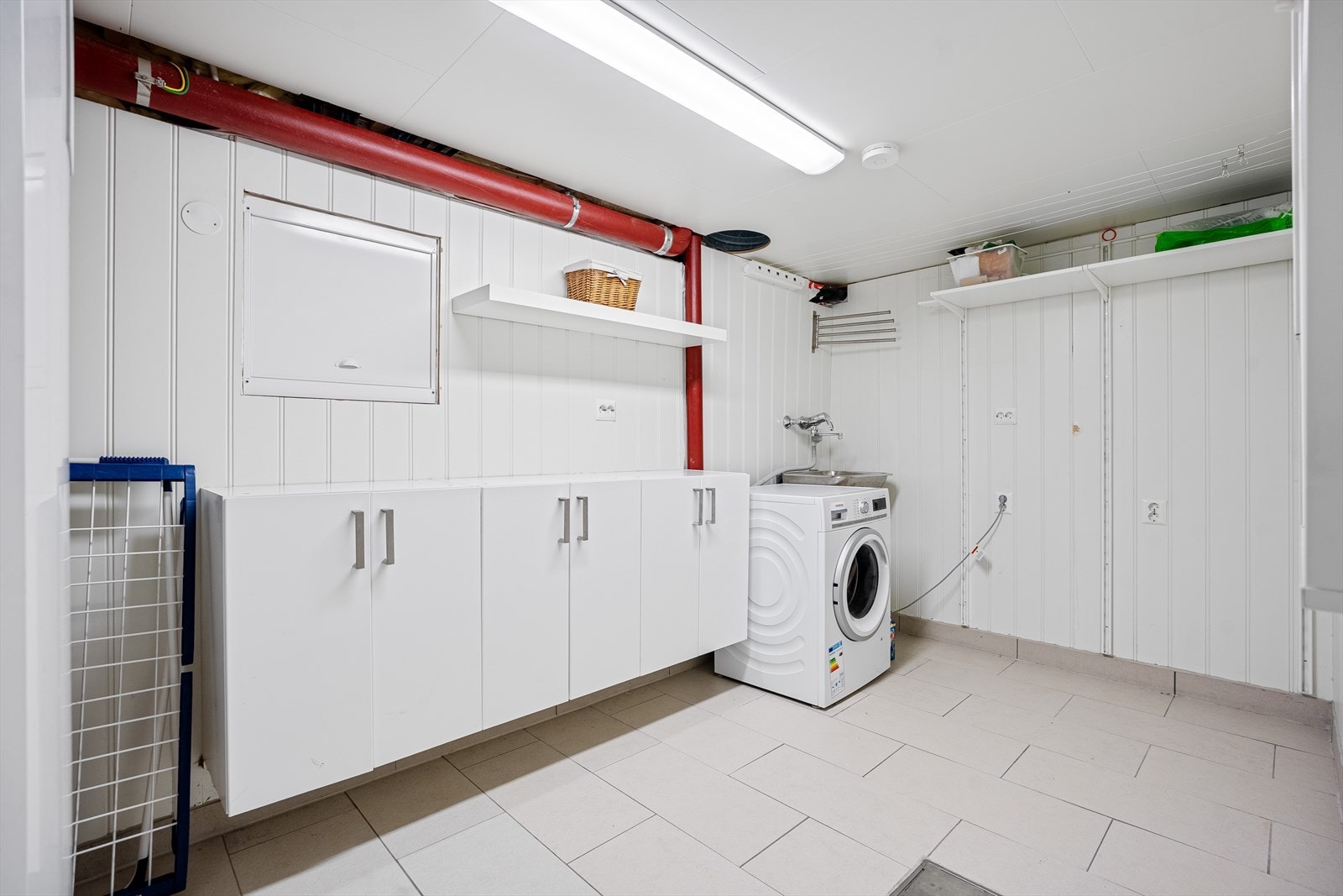 Romslig og praktisk vaskerom i kjeller. Fliser på gulv med varme. Galleribilde