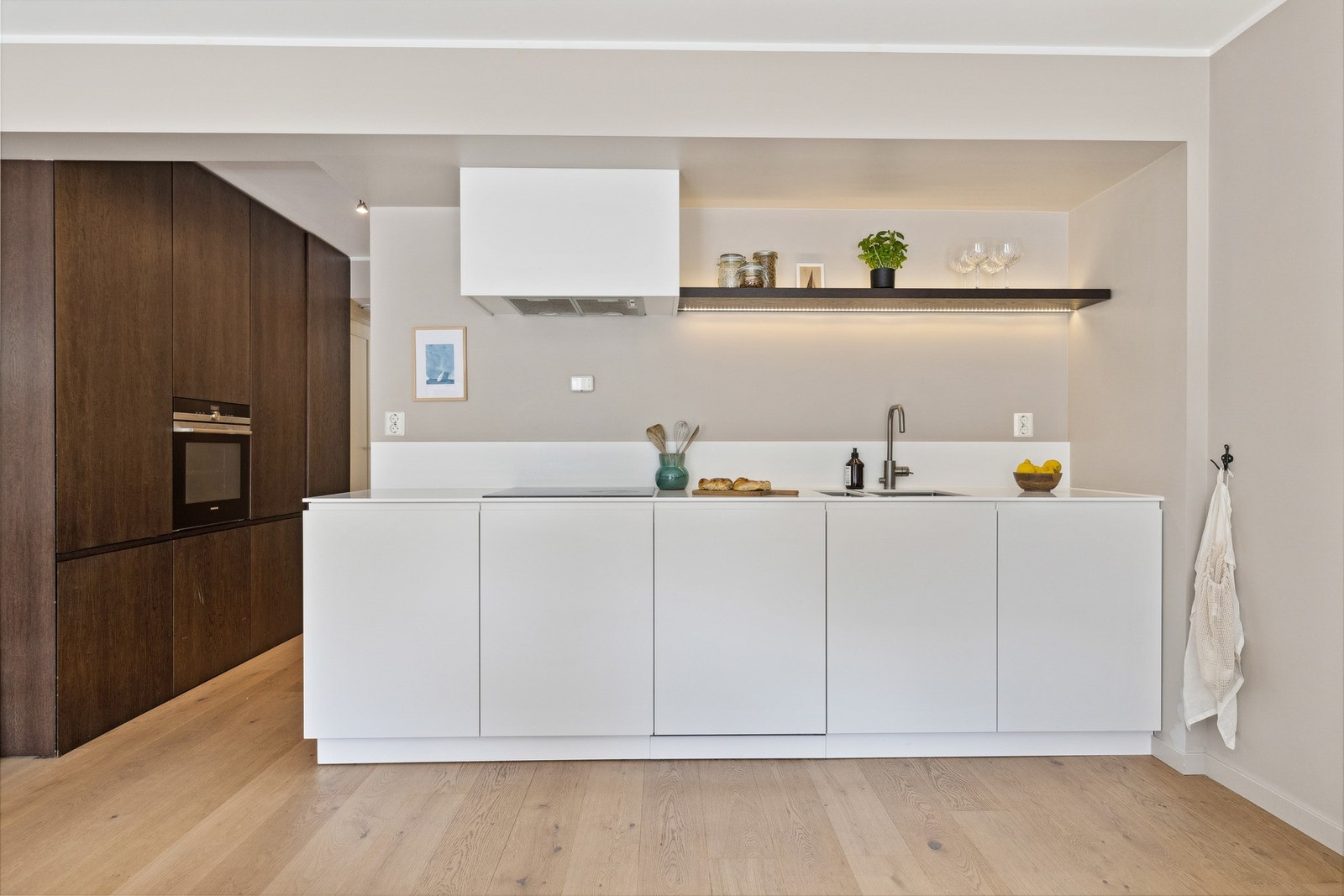 Kjøkkenet fremstår tidløst og moderne med glatte fronter og benkeplate i stein Galleribilde