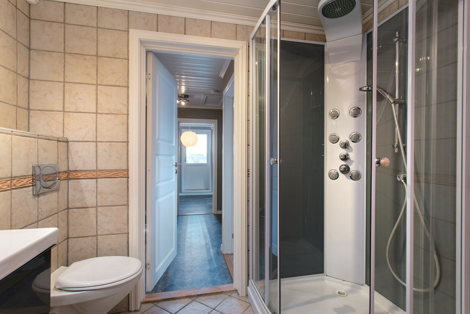 Badet har vegghengt wc samt dusjkabinett med dusjarmatur Galleribilde