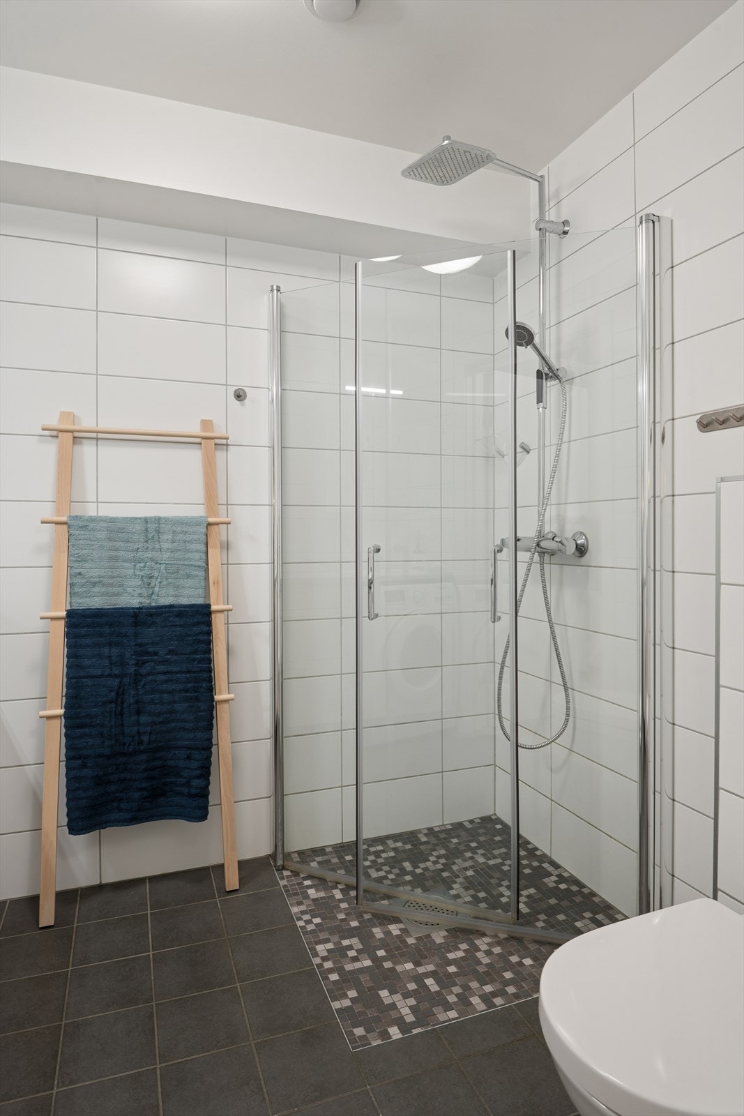 Badet er også utstyrt med regnfallsdusj, vegghengt toalett og speilskap med belysning Galleribilde