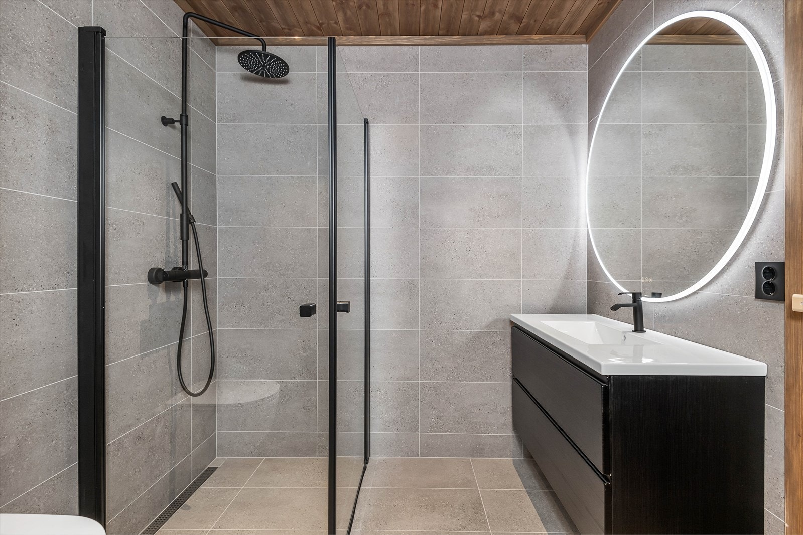 Hovedbadet er plassert i underetasjen sammen med de 4 soverommene. Lekkert fargevalg på fliser. Dusj med glassvegger, servantinnredning med skuffer for oppbevaring og wc. Galleribilde