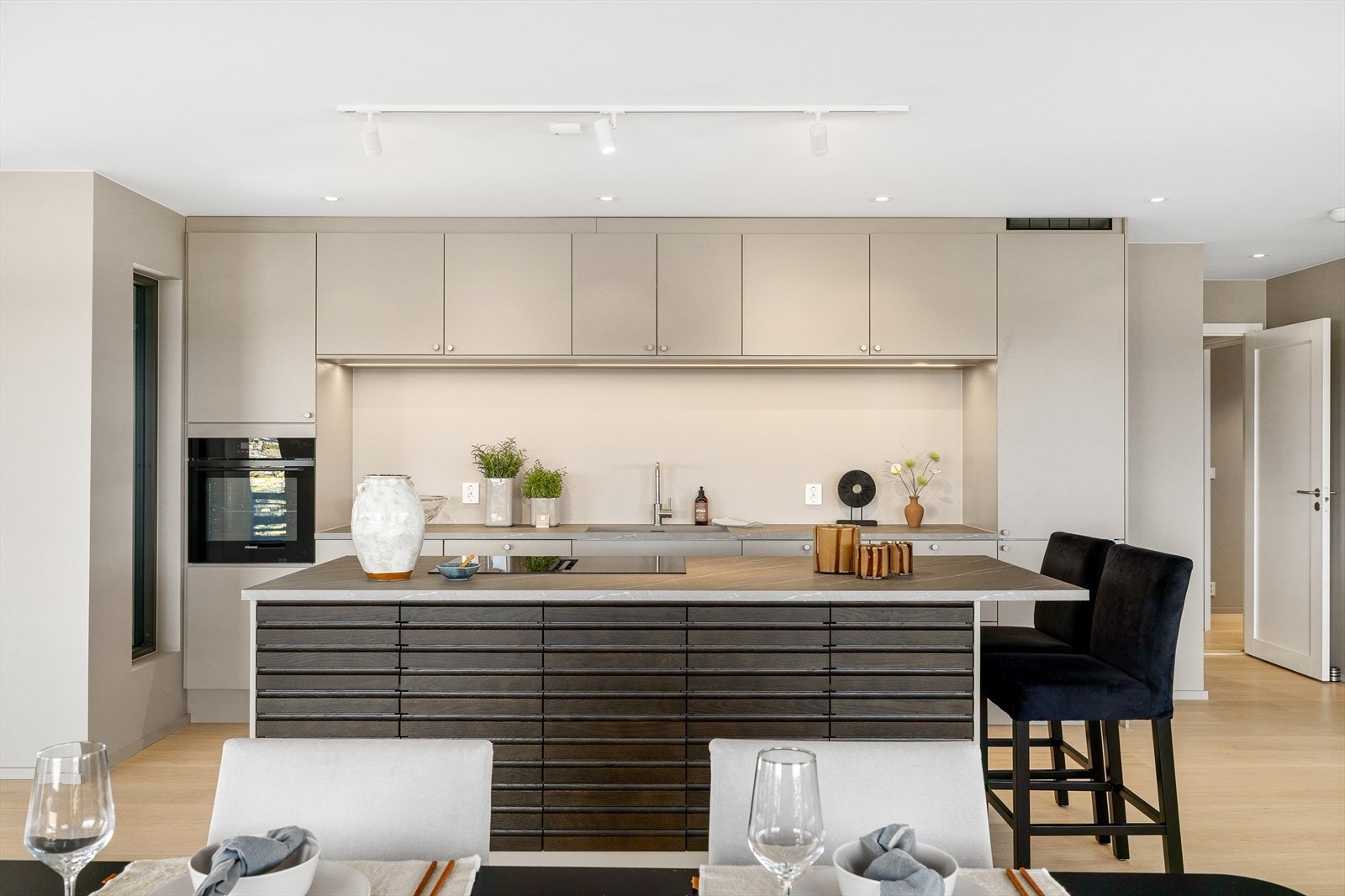 Det er godt med lagringsplass i over- og underskap, og smarte løsninger gir deg et oversiktlig og ryddig kjøkkenmiljø. De integrerte hvitevarene glir sømløst inn i helheten og gir en ren og moderne finish. Galleribilde