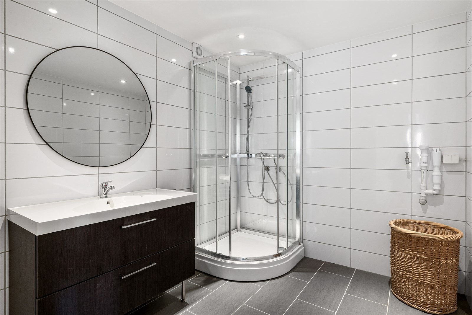 Baderommet har flis på vegger og tak har malte plater m/downlights. Gulvet er flislagt. Rommet har elektriske varmekabler. Rommet har innredning med nedfelt servant, dusjkabinett, speil og opplegg til vaskemaskin. Galleribilde